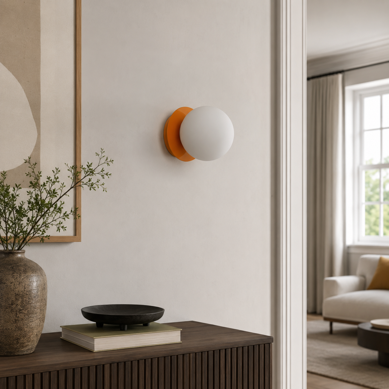Una lámpara de pared con base naranja y globo de cristal blanco cuelga sobre un armario de madera.