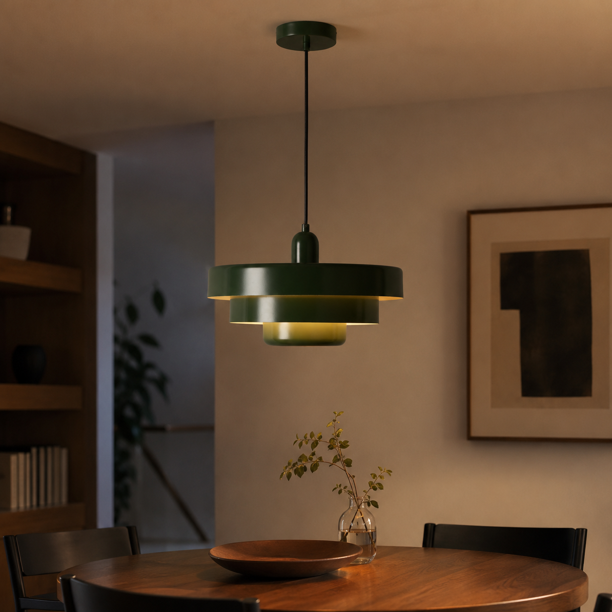 Una lámpara colgante verde sobre una mesa de madera con jarrón y cuenco.