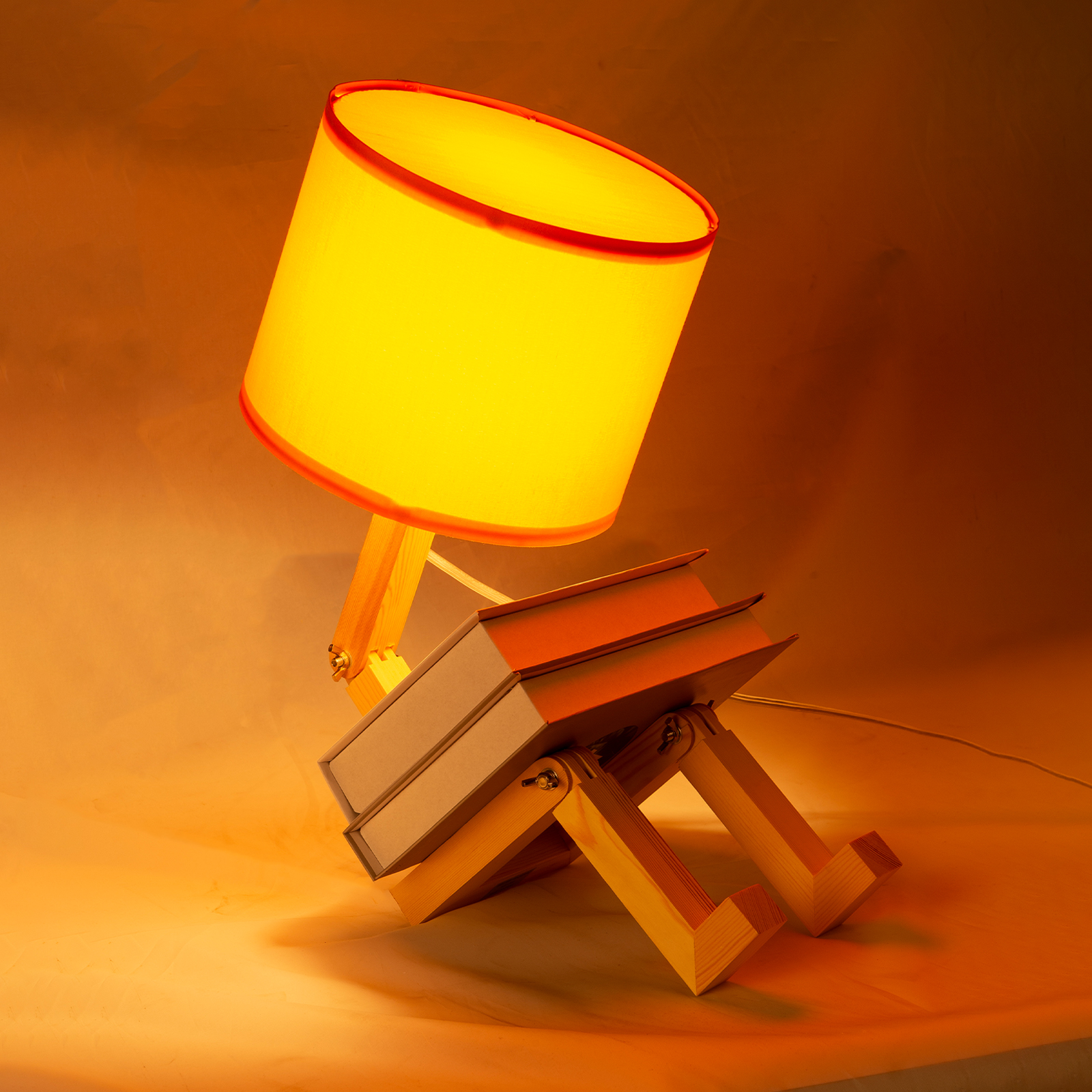 Una pantalla de lámpara amarilla brilla sobre un soporte de madera que parece libros.