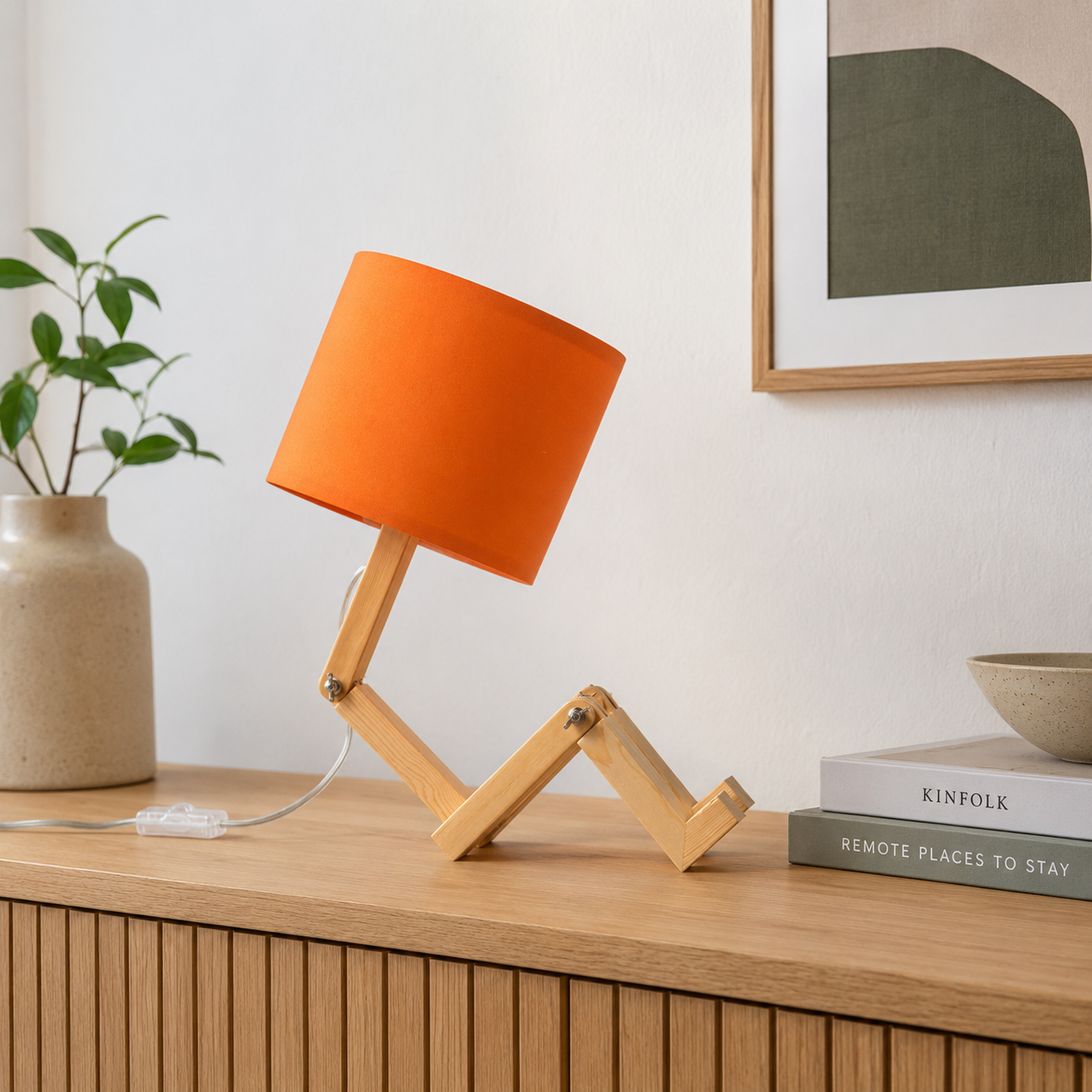 Una lámpara de escritorio naranja con juntas articuladas de madera en un mueble.