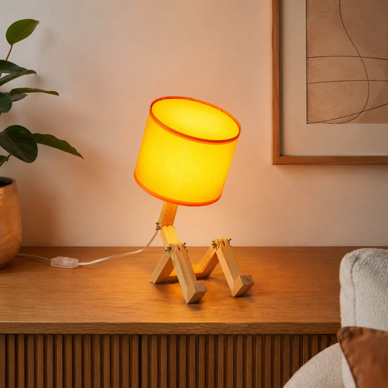 Una lámpara con pantalla amarilla y patas de madera está sobre un mueble.