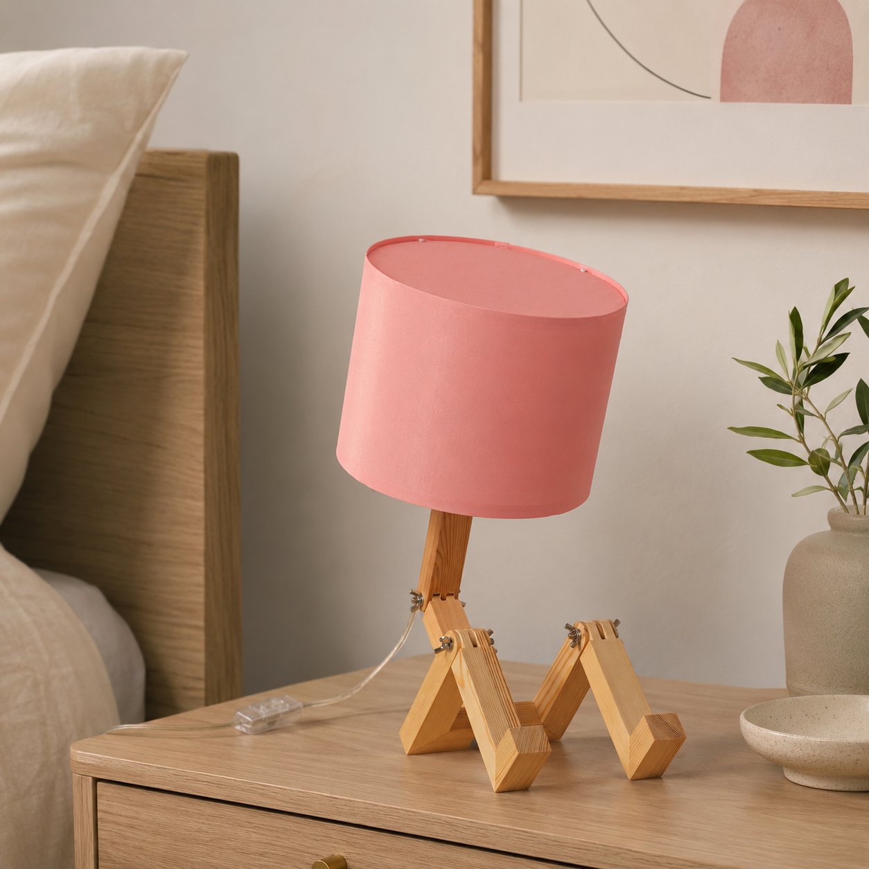 Una pantalla de lámpara rosa sobre una base de madera en una mesita de noche.