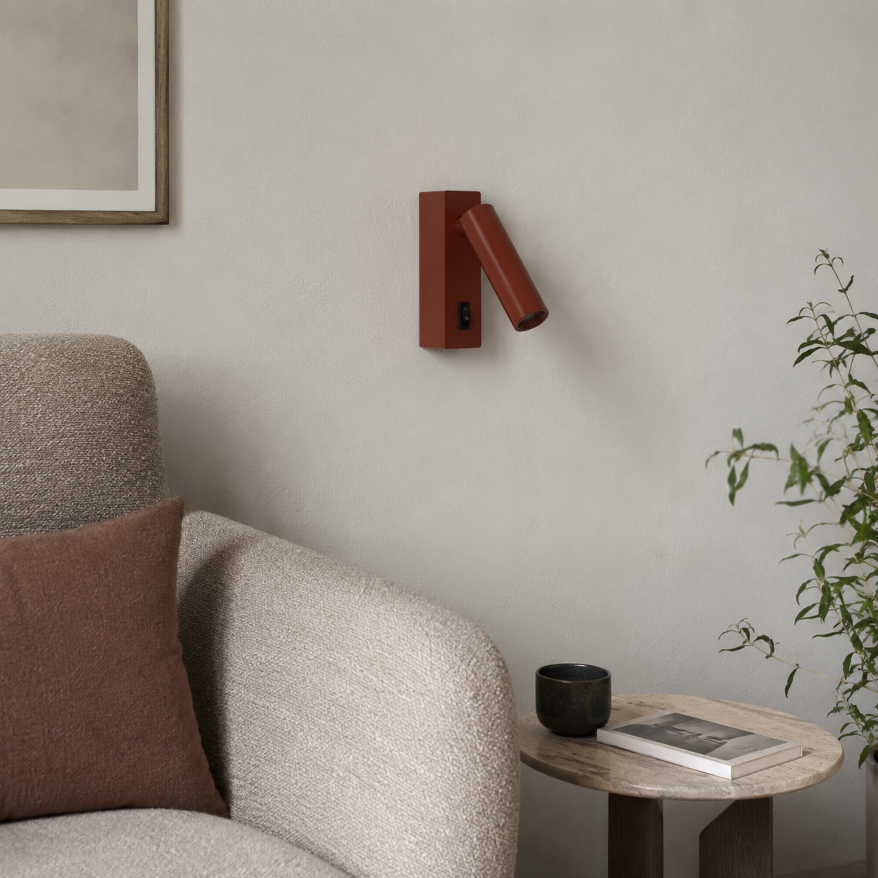 Un aplique de pared rojo sobre un sillón con cojín y mesa auxiliar.