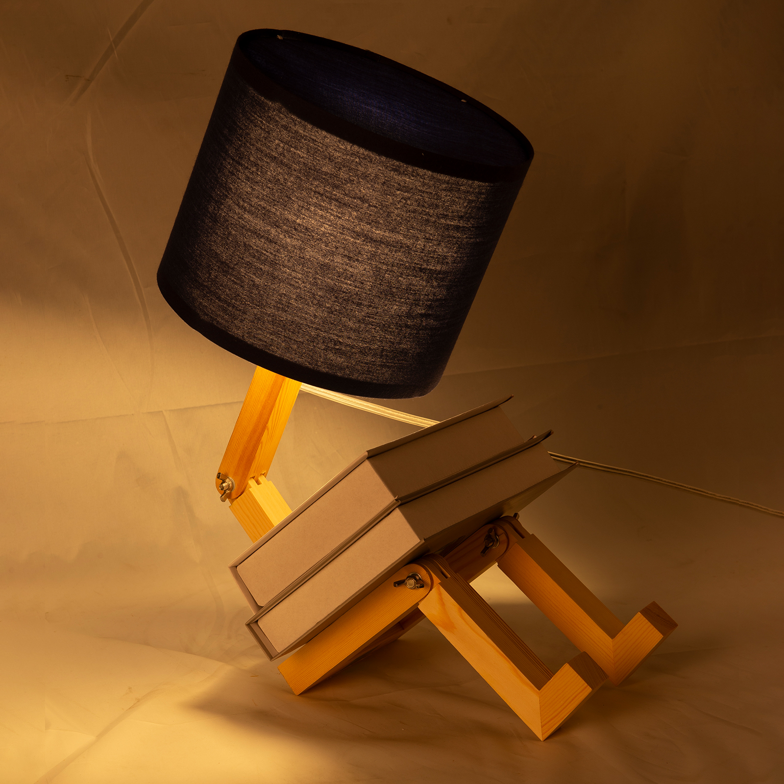 Una lámpara de escritorio con pantalla oscura sobre juntas de madera, que parece un libro.