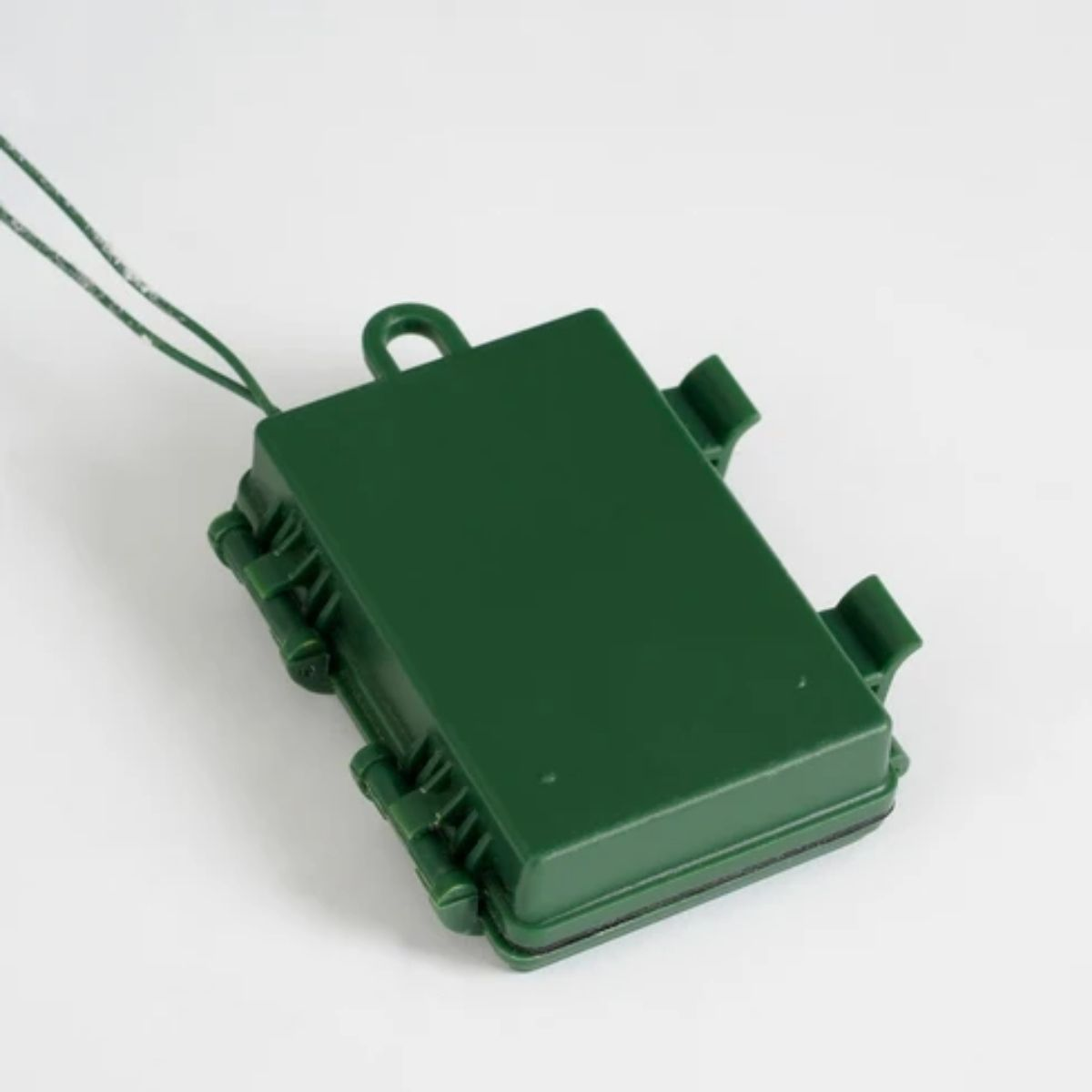 A green battery compartment with clips and a hanging loop.