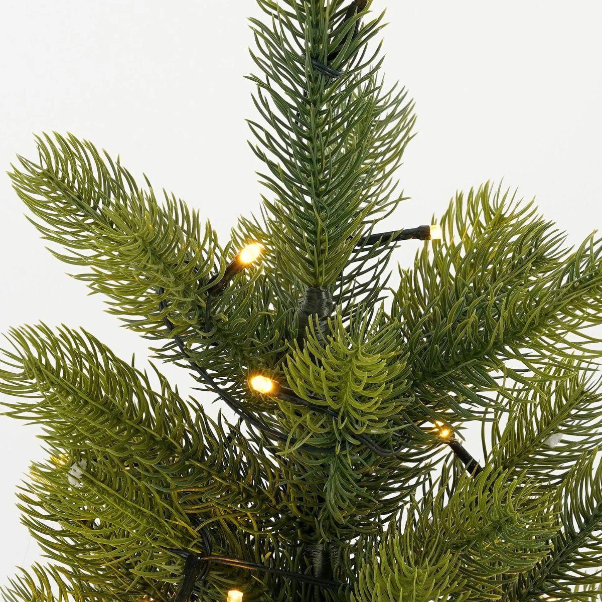 Close-up of a green artificial fir tree with small lights.