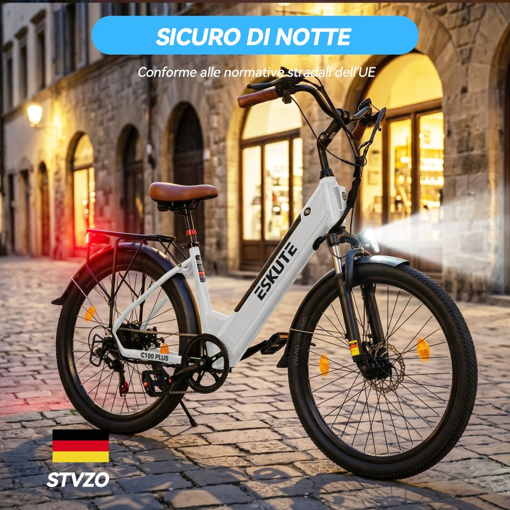 Una e-bike bianca si trova di notte su una strada acciottolata davanti agli edifici.