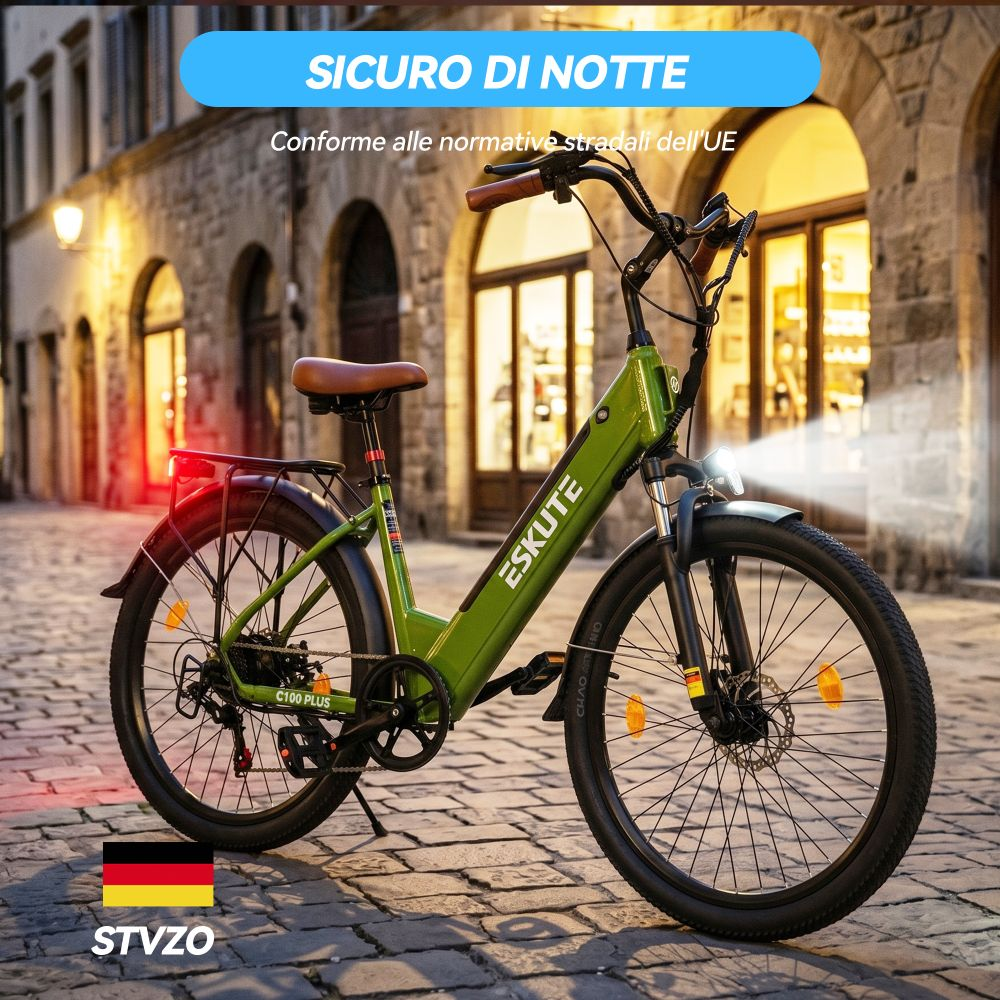 Bici elettrica verde con sella marrone, su strada acciottolata, scatto notturno con luci.