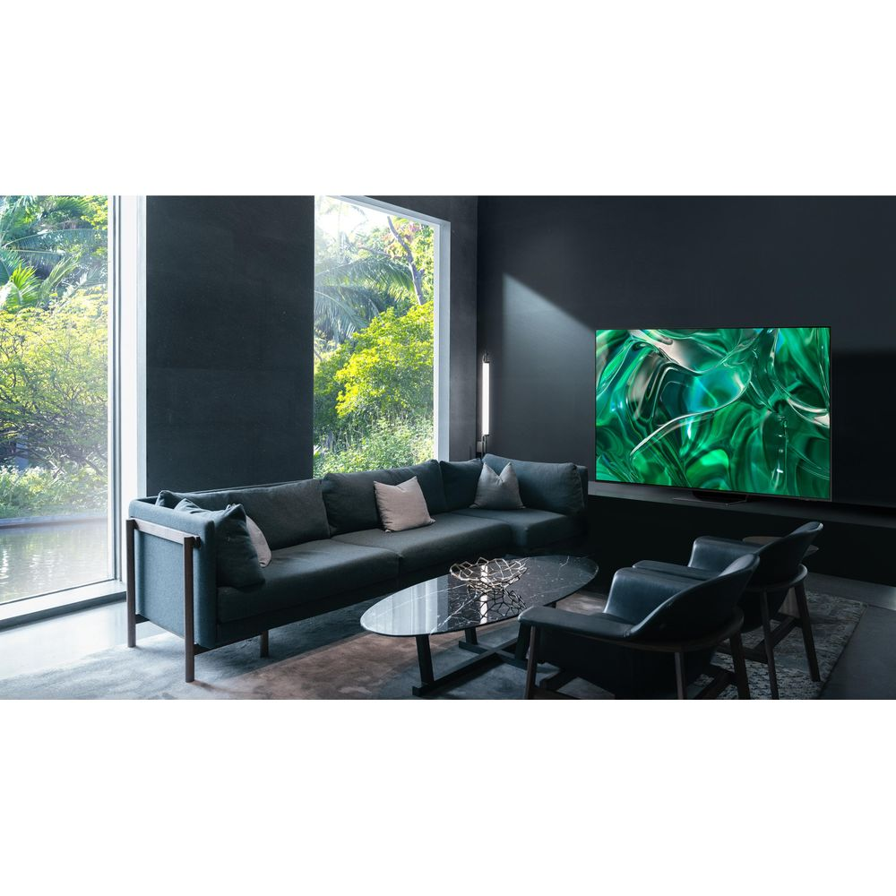 Soggiorno moderno con divano angolare grigio scuro, tavolino in vetro e TV che mostra arte astratta verde.