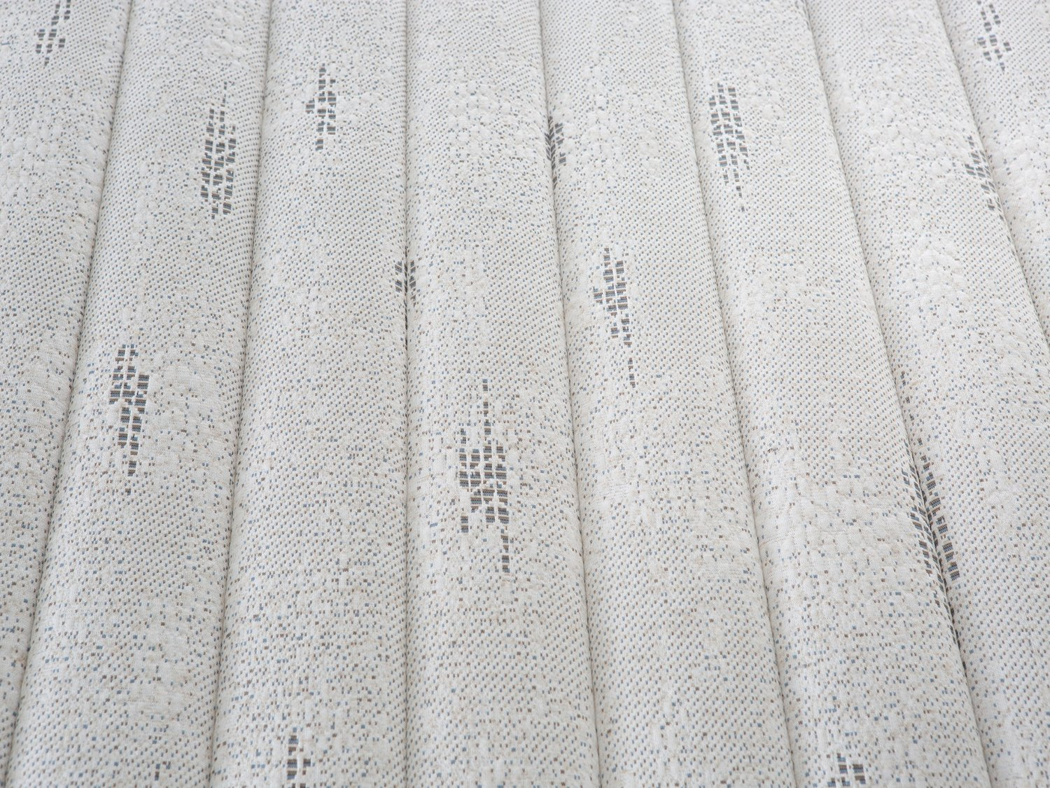 Primer plano de un colchón blanco con patrón texturizado y sutiles detalles de costura gris.