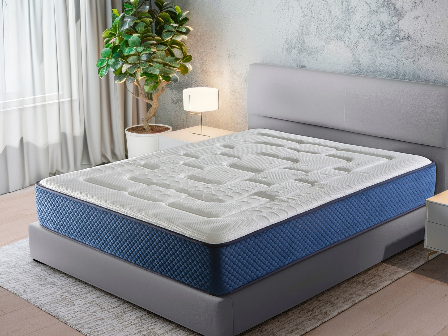 Un colchón blanco acolchado con laterales azules sobre una cama.
