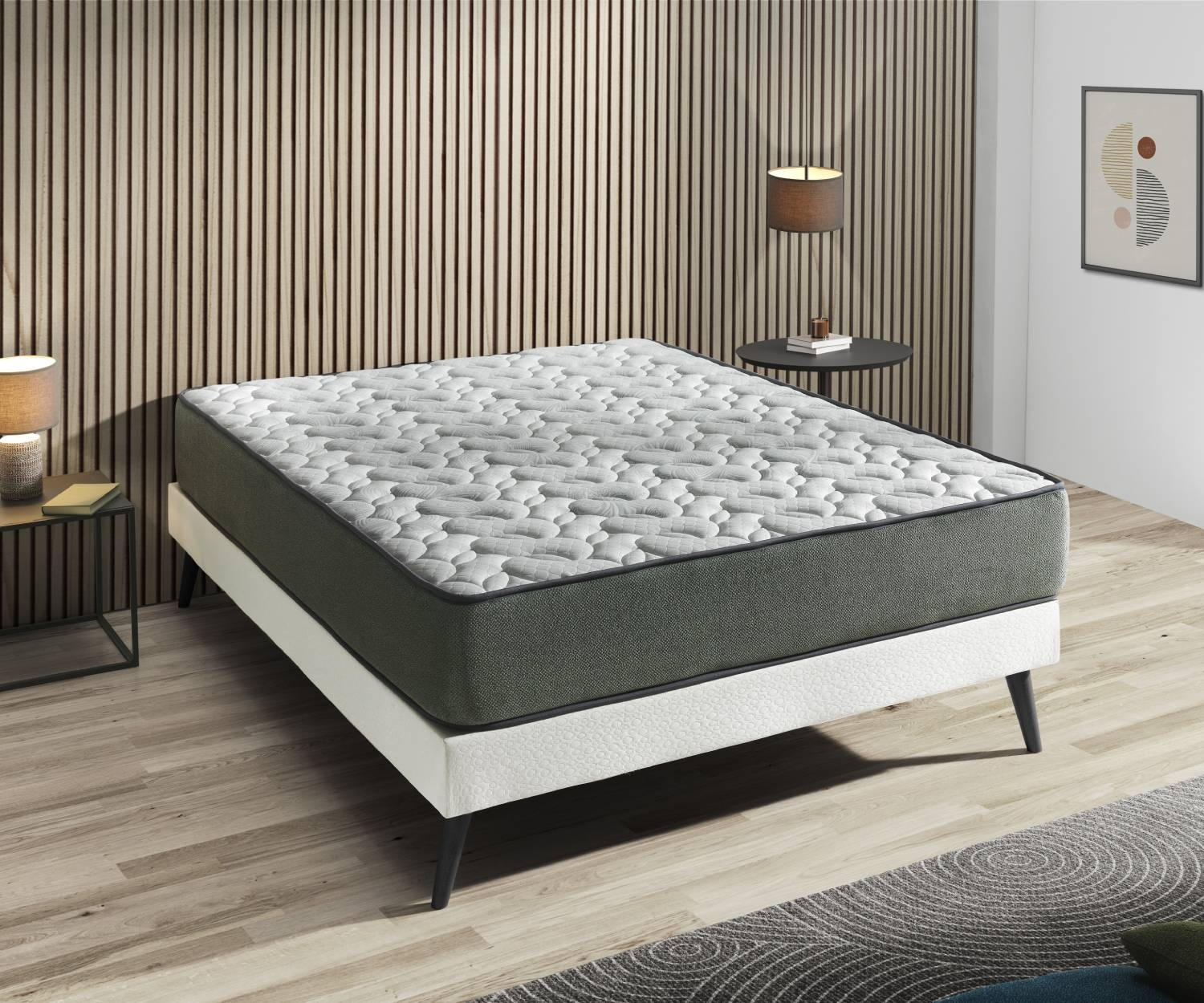 Una cama blanca con un colchón gris y blanco se alza sobre un suelo de madera.
