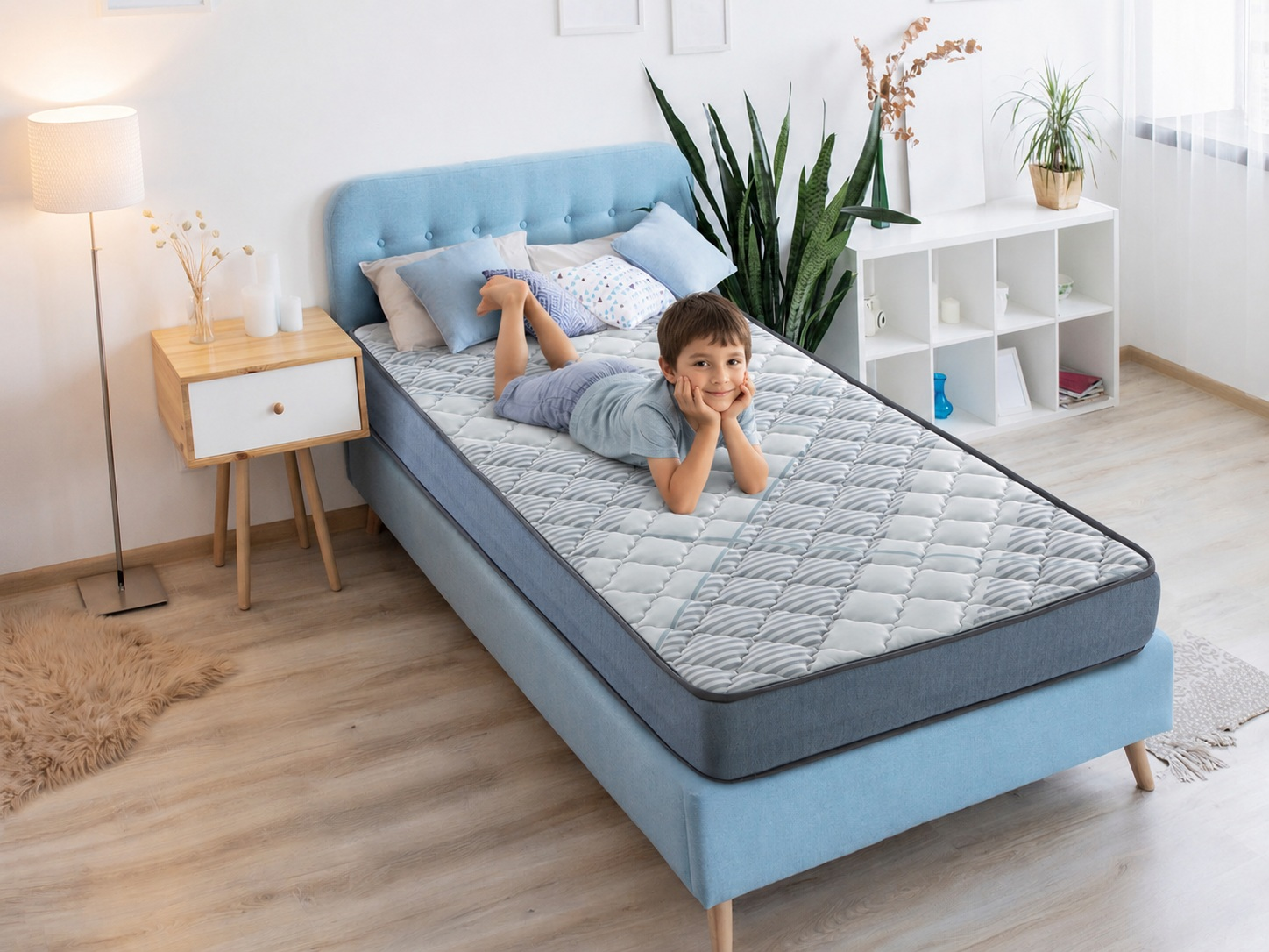 Un niño yace en una cama con un colchón de patrón gris.