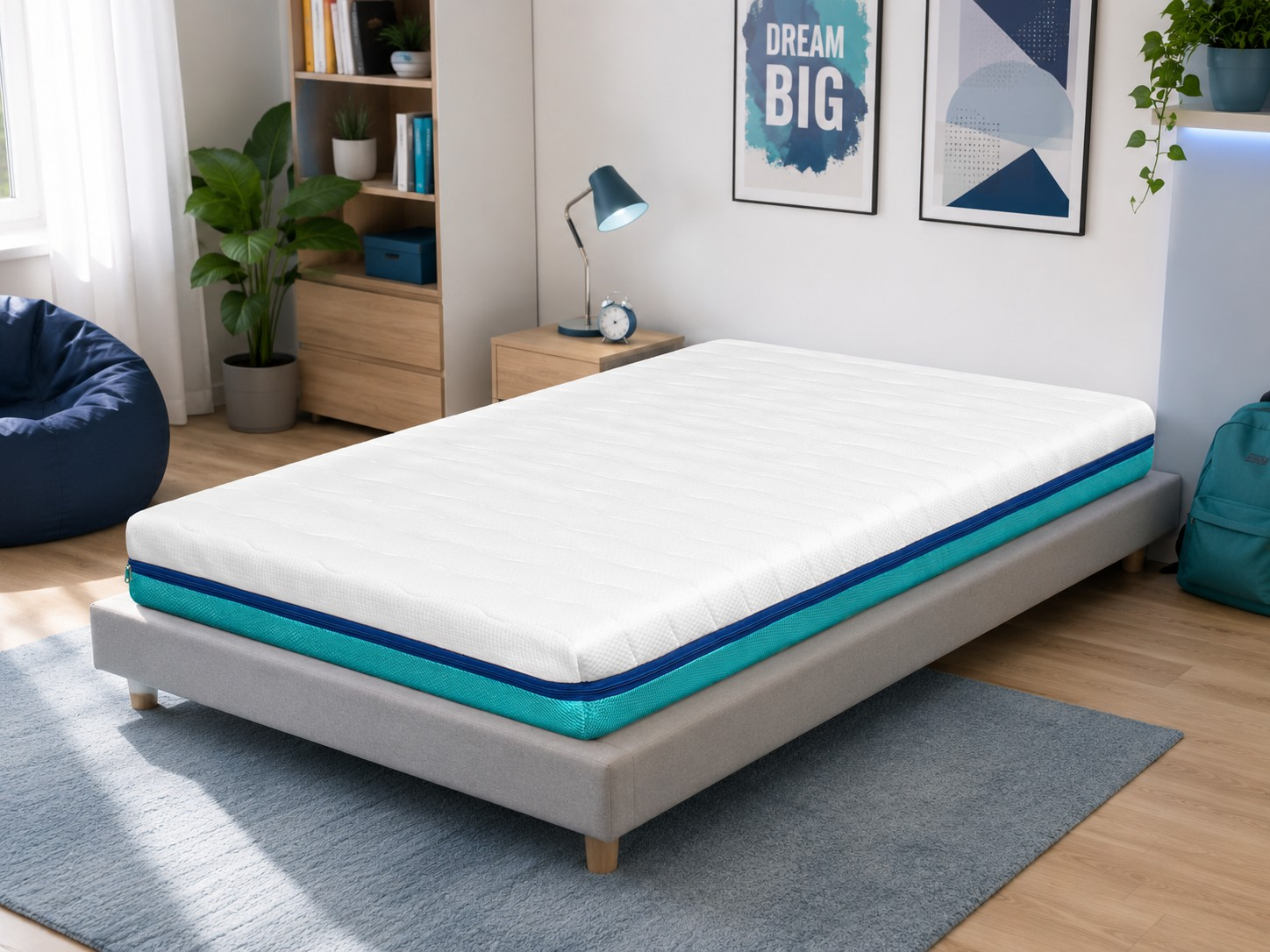 Un colchón blanco con ribete azul y turquesa sobre un somier gris en un dormitorio.