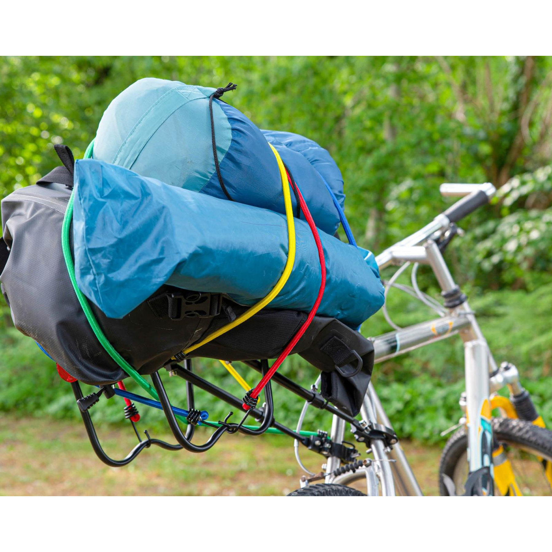 Fiets met bagagedrager beladen met blauwe en groene slaapzakken en tassen.