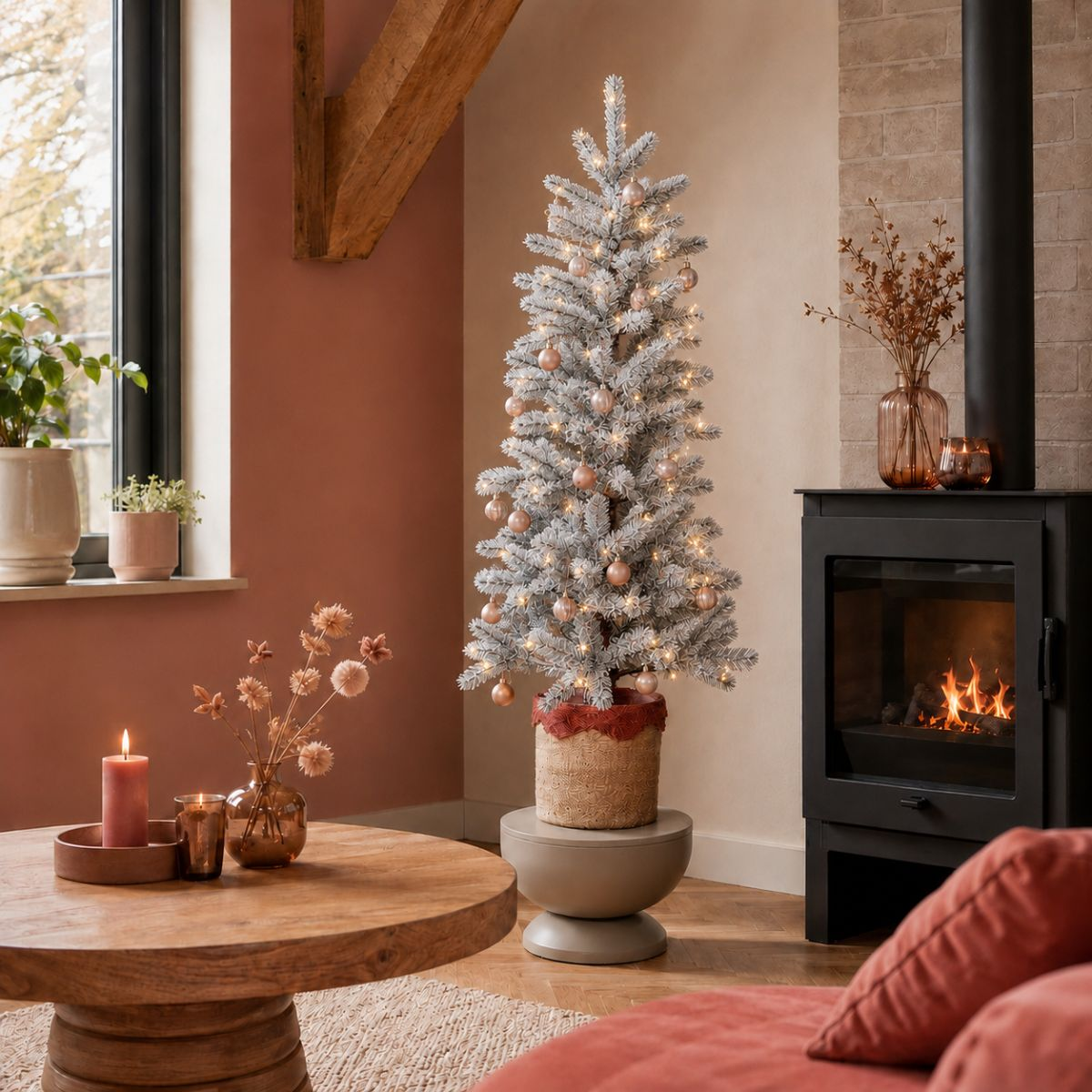 Ein gemütliches Wohnzimmer mit einem beflockten Weihnachtsbaum, Kamin und Holztisch.