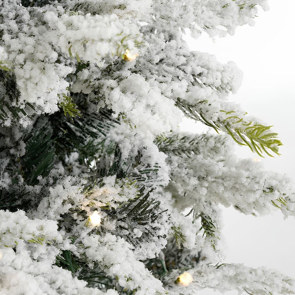 Snow-covered pine branches with small lights, close-up.
