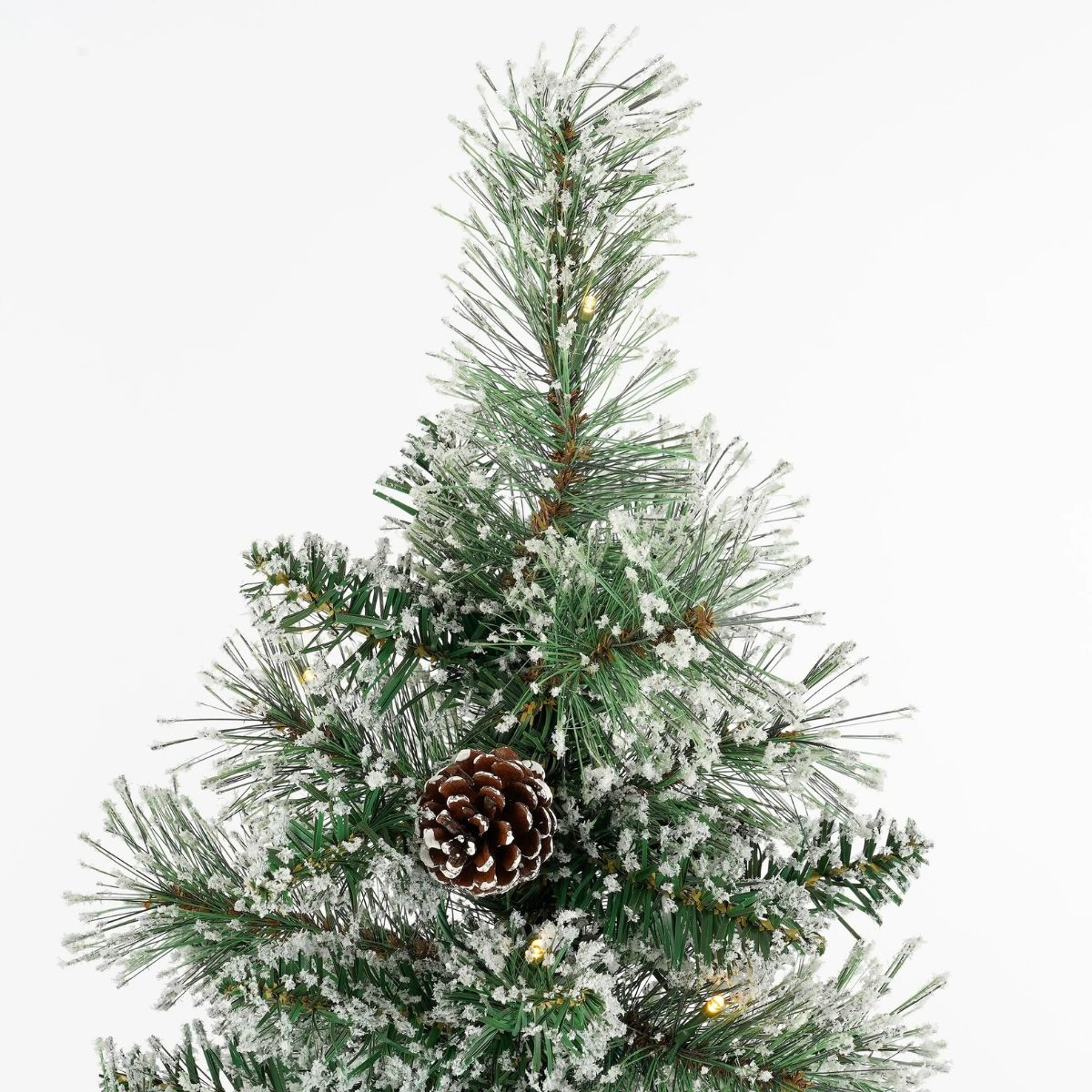 Close-up of an artificial Christmas tree with faux snow, pinecone, and lights.
