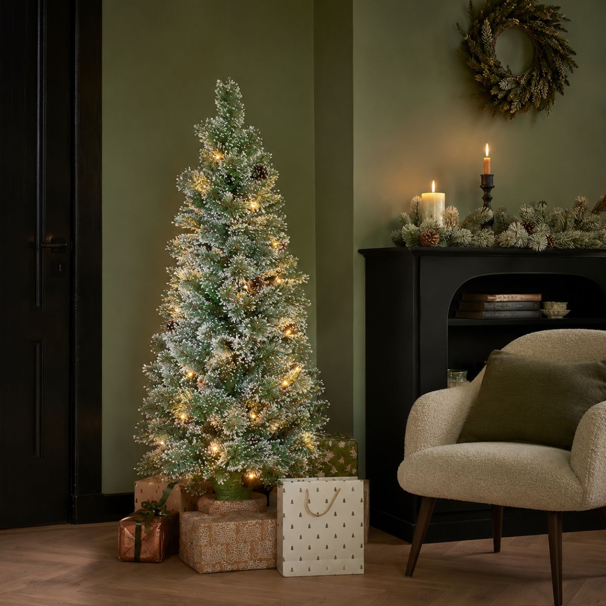 A decorated Christmas tree with lights stands beside gifts and a cozy chair.
