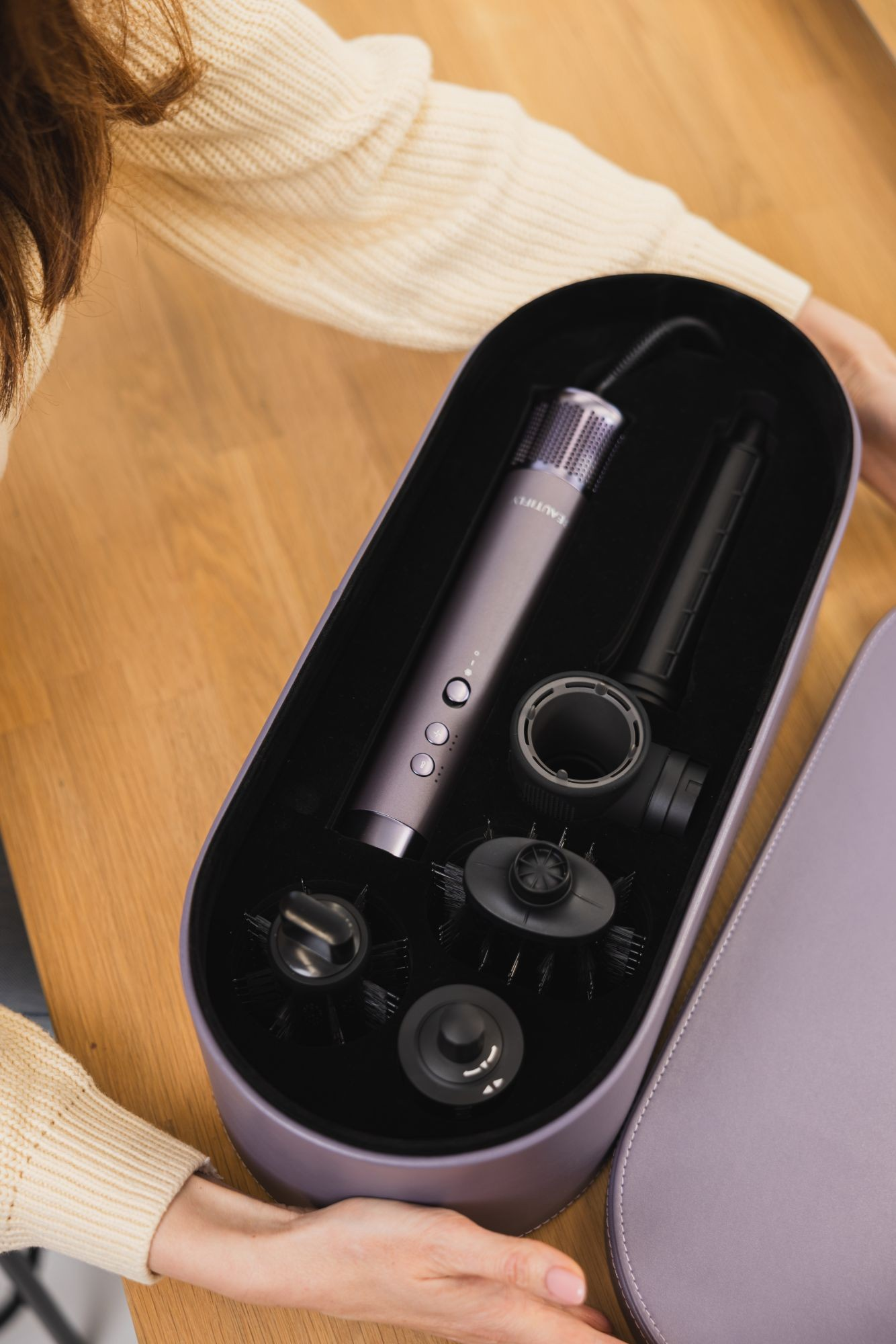 Una custodia viola con asciugacapelli viola e accessori su un tavolo di legno.