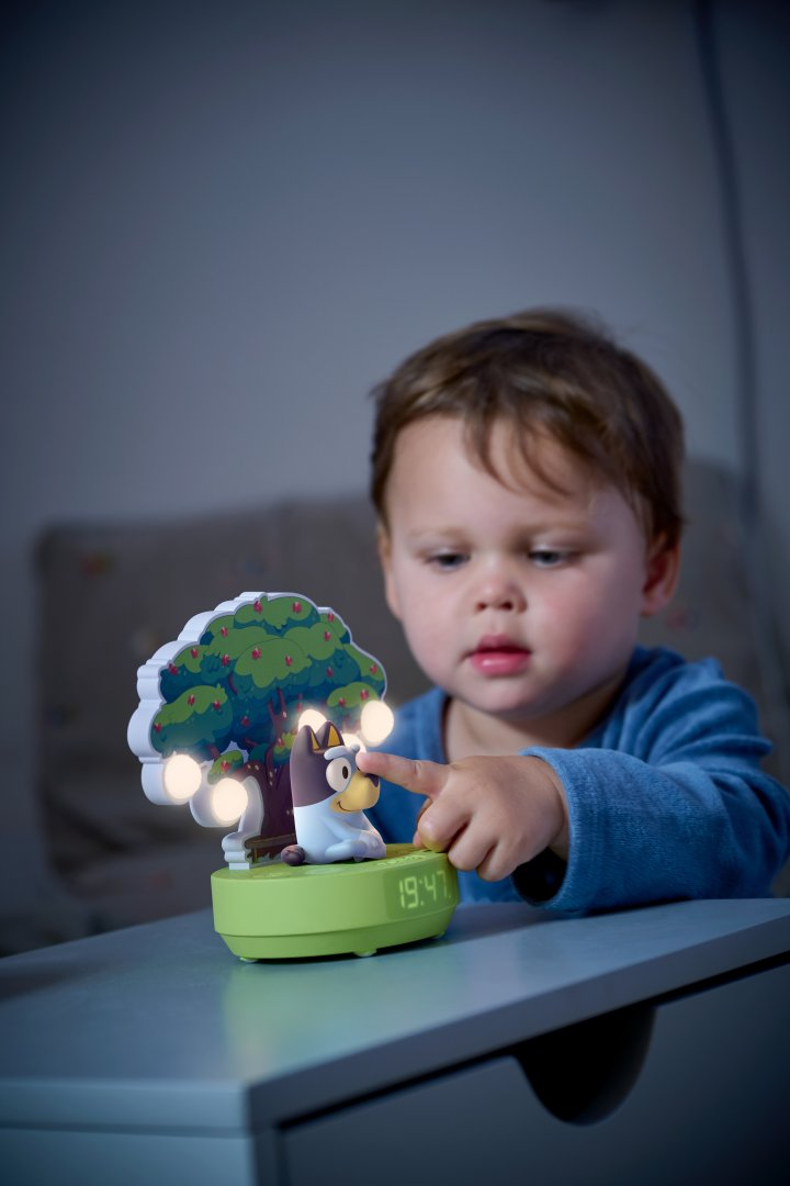 Un enfant touche une lampe avec un chien et un arbre.