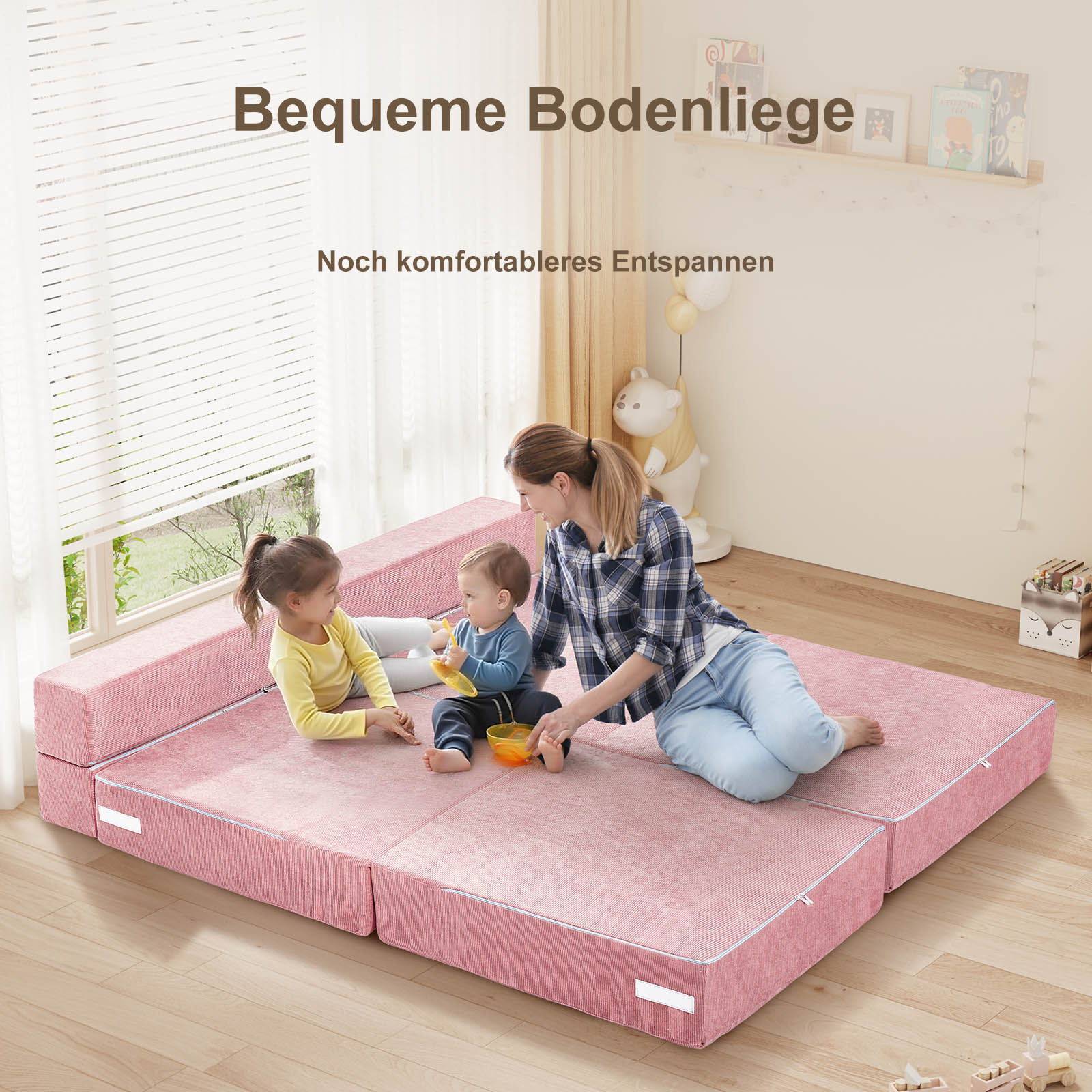 Eine Frau sitzt mit zwei Kindern auf einem rosafarbenen Bodenkissen.