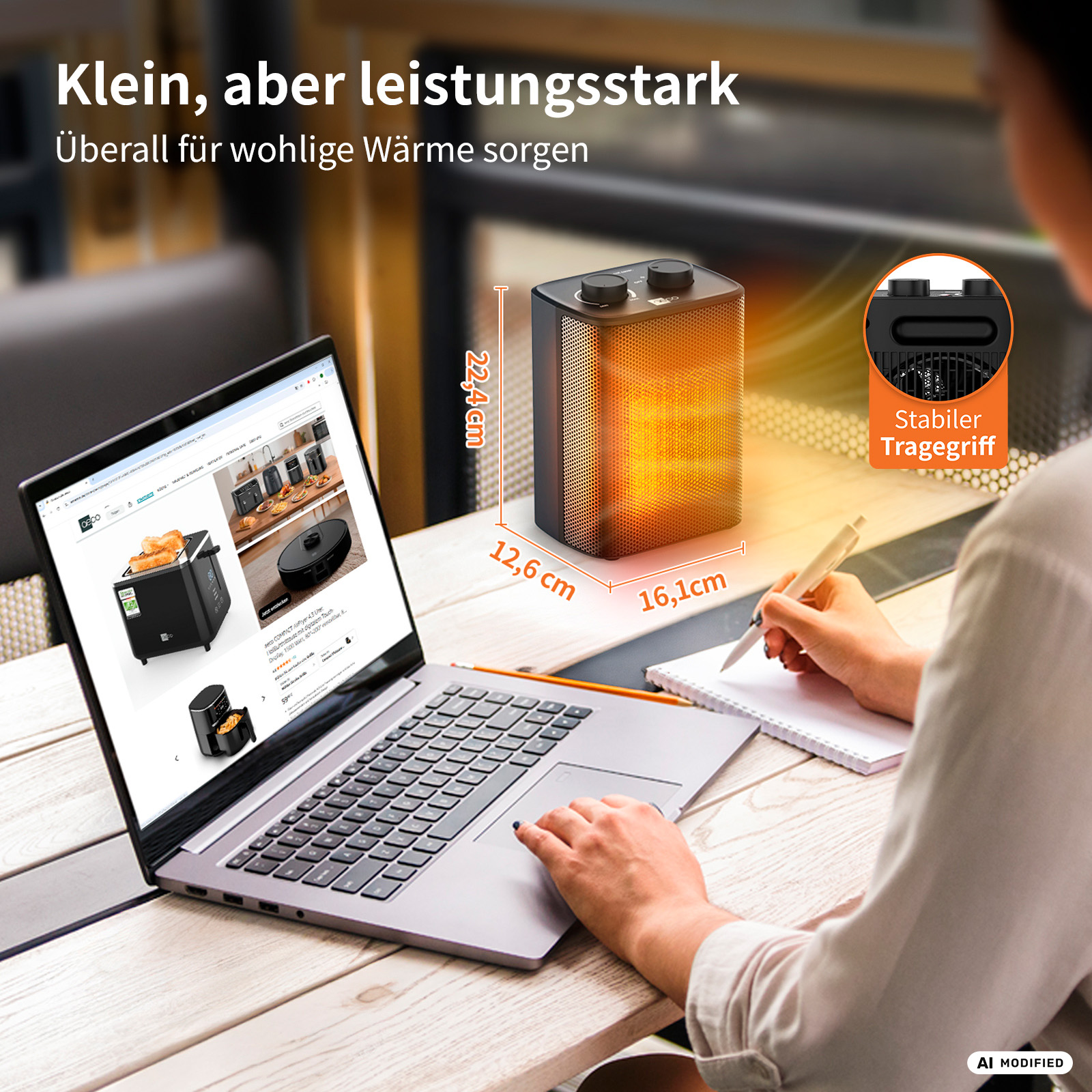 Ein kleiner Heizlüfter mit Laptop und Notizblock auf einem Tisch.