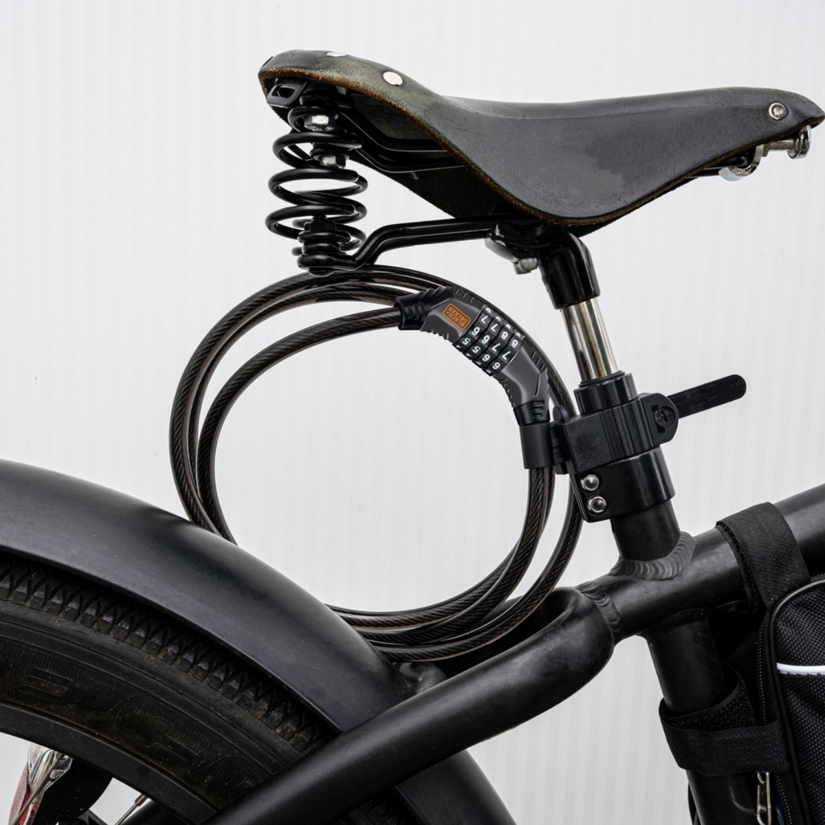 A black bicycle with a coiled cable lock wrapped around the seat post and frame.