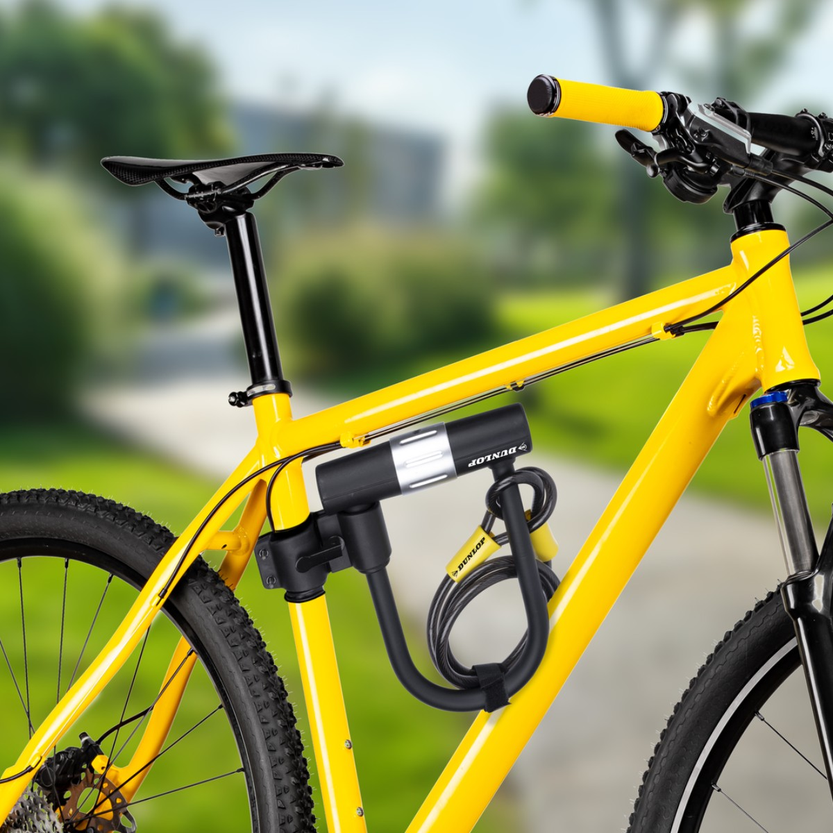Ein gelbes Fahrrad mit einem schwarzen Dunlop-Schloss am Rahmen. Draußen.