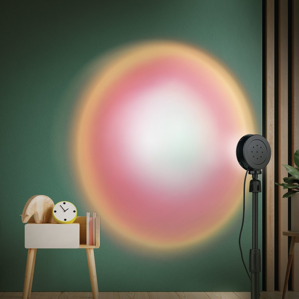 Een zwarte zonsonderganglamp projecteert een kleurrijke, cirkelvormige gradiënt op een getextureerde groene muur, met een houten bijzettafel en decoratie.