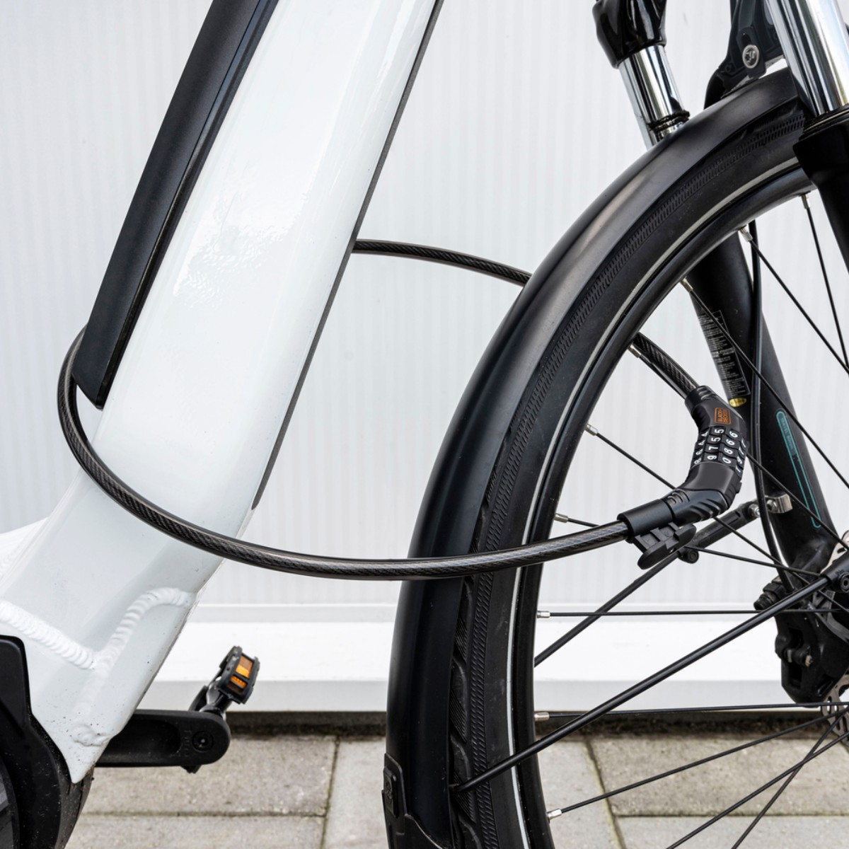 A white bicycle with a black cable lock wrapped around the frame and front wheel.
