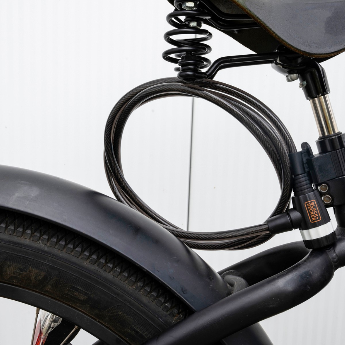 Black bicycle with a lock coiled around the seat and rear wheel, against a white background.