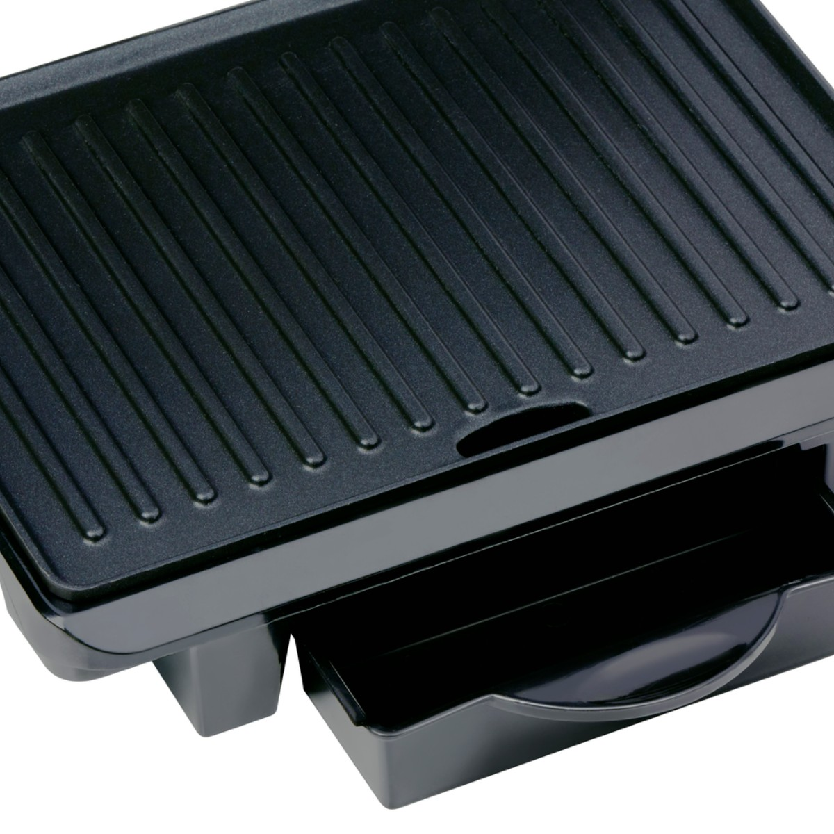 Nahaufnahme einer schwarzen Grillplatte mit Rillen und einer ausziehbaren Schublade.