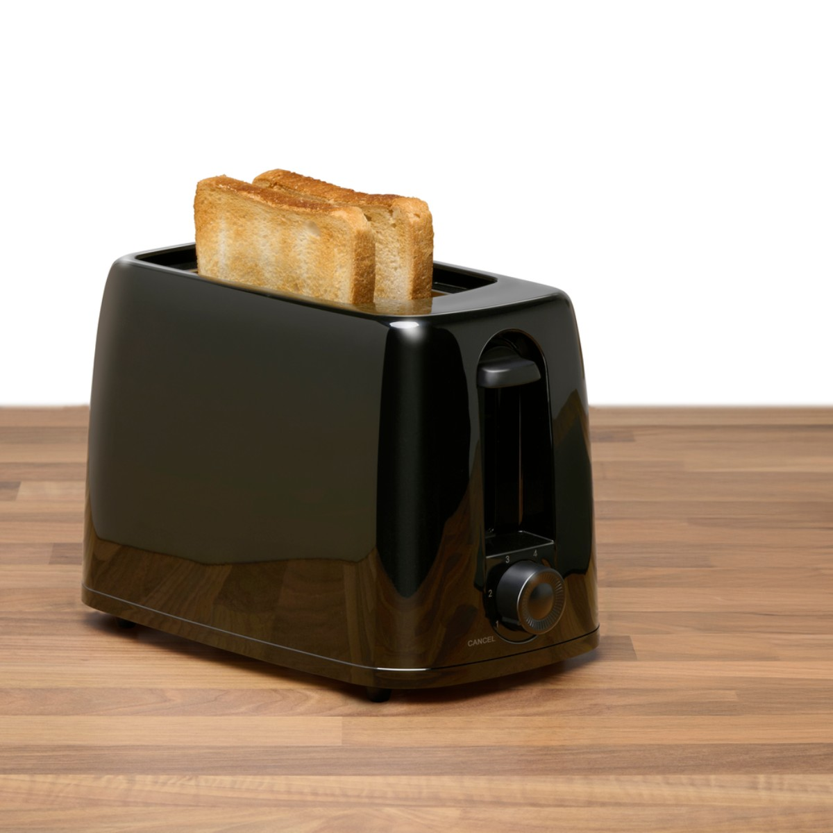 A black toaster with two slices of toast on a wooden table.