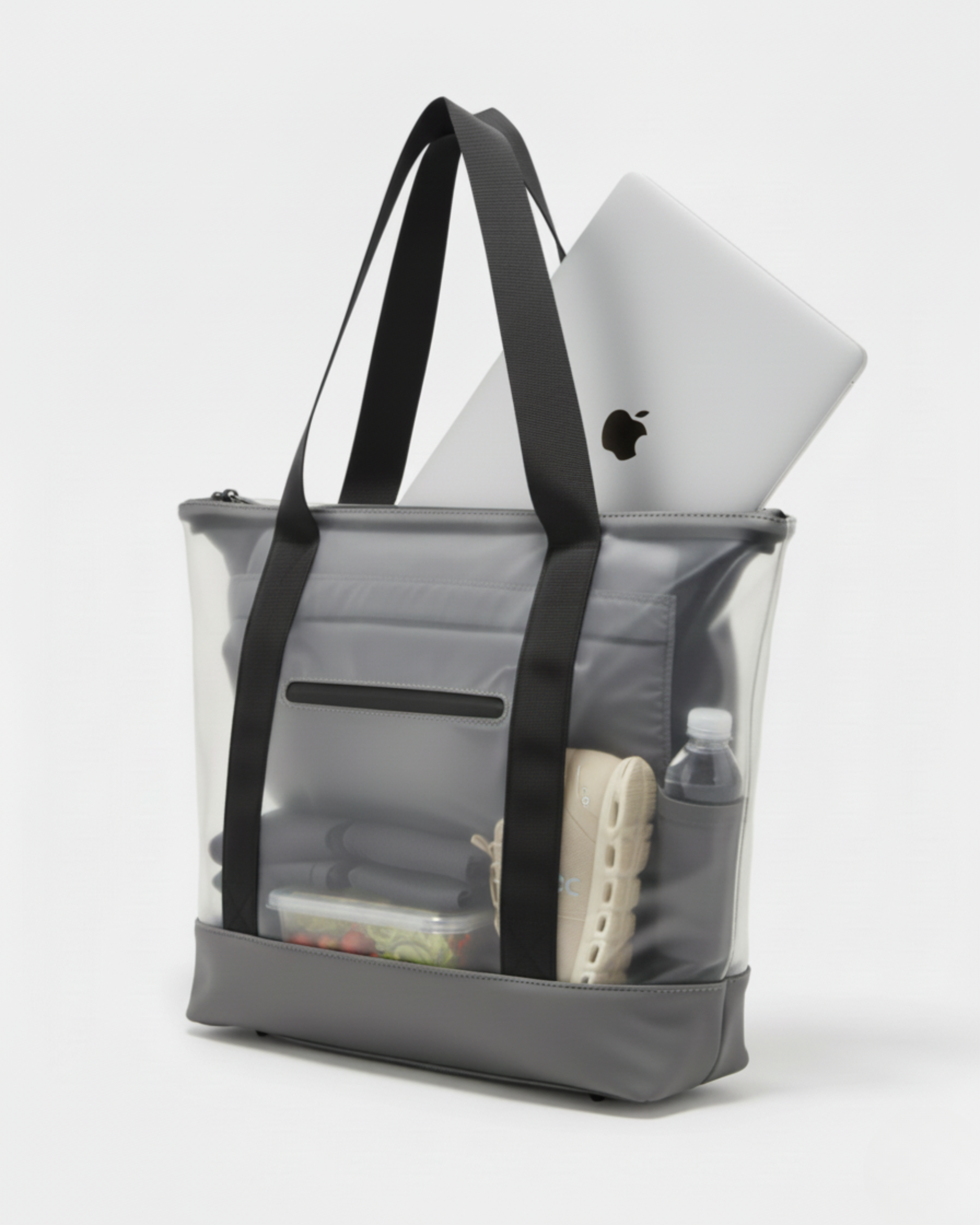 Una borsa tote grigia trasparente con cinghie nere, contenente un laptop argentato, una scarpa beige, una bottiglia d'acqua e un contenitore per alimenti.