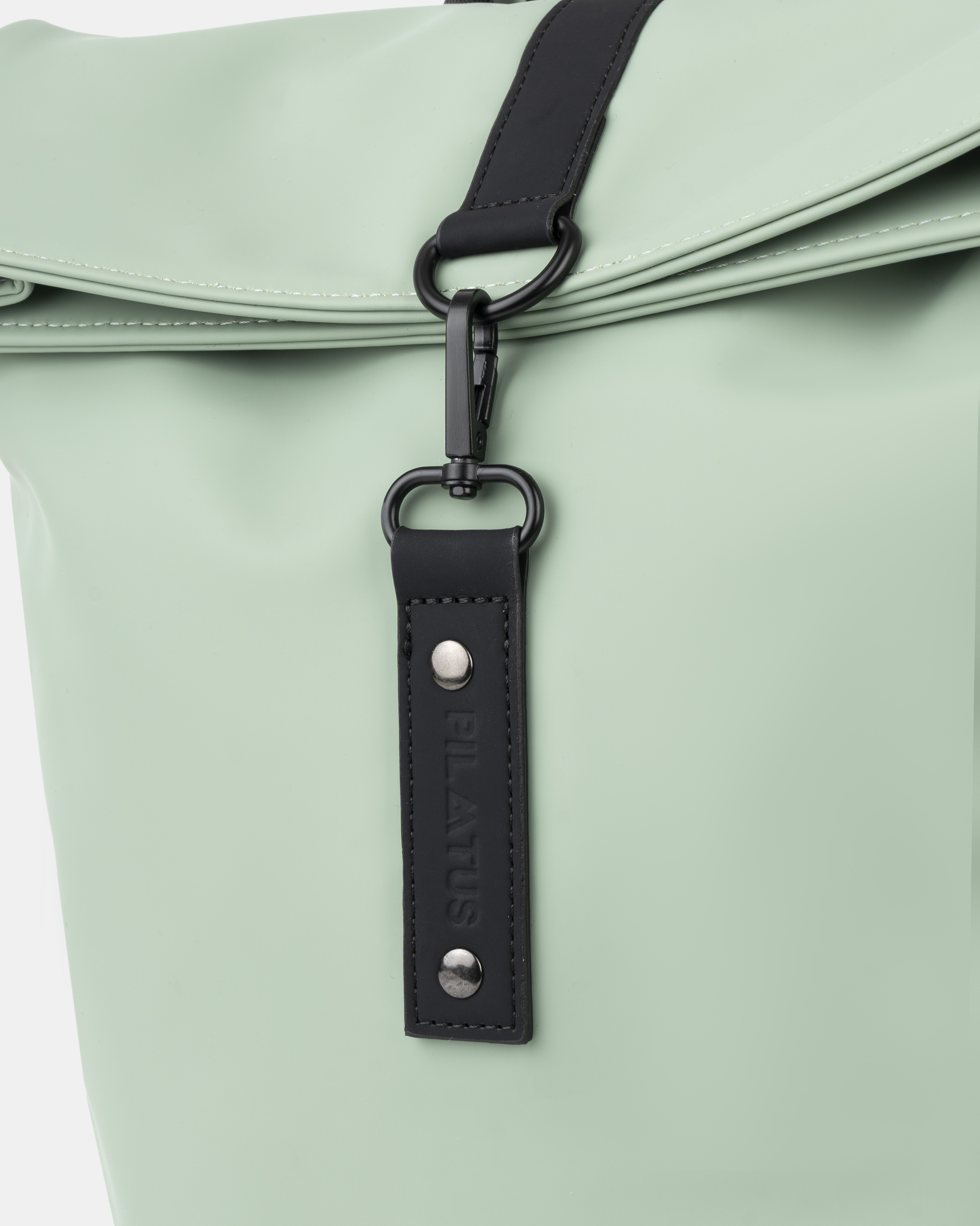 Zaino verde menta chiaro con etichetta in pelle nera e moschettone.