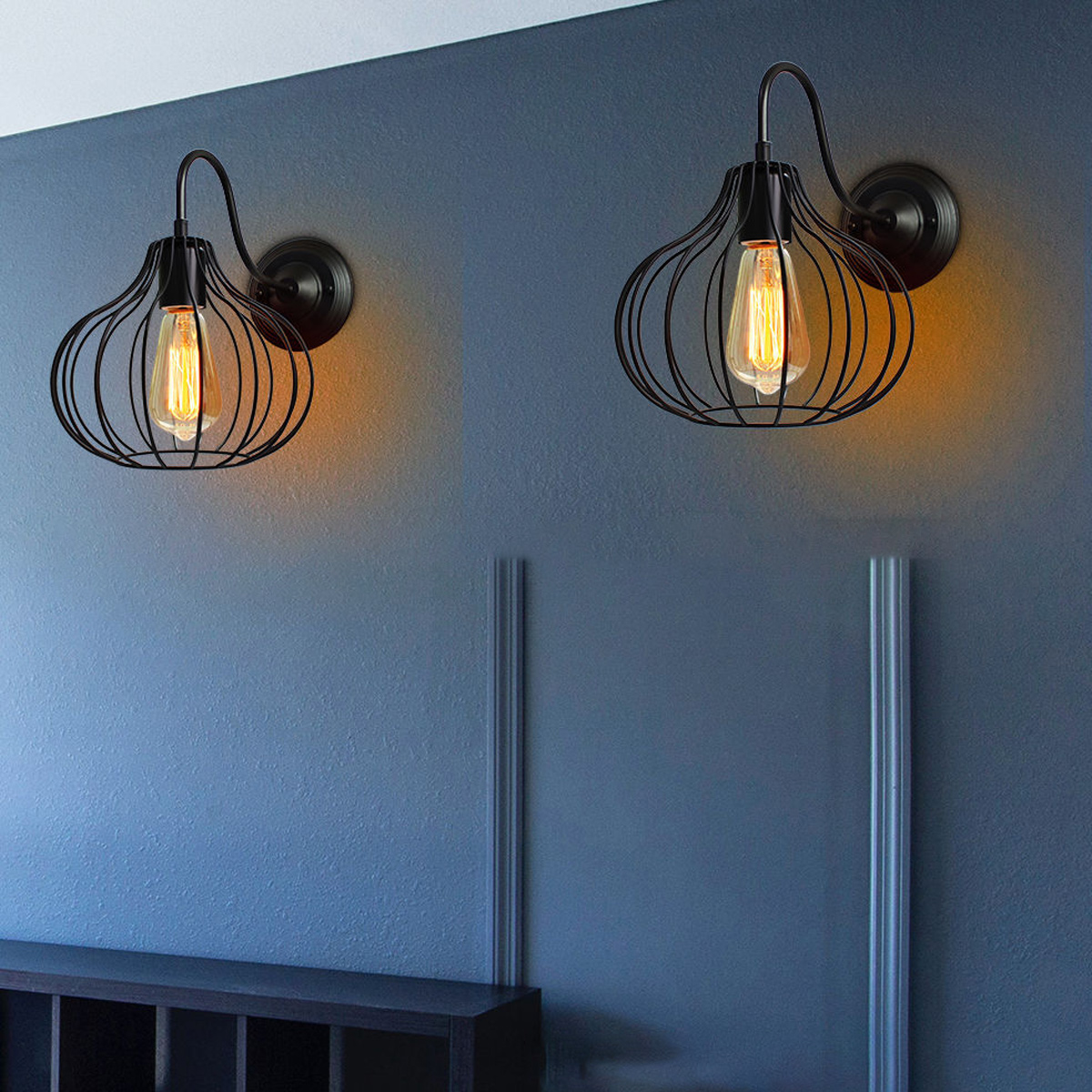 Zwei schwarze Wandleuchten mit Glühbirnen an einer blauen Wand.