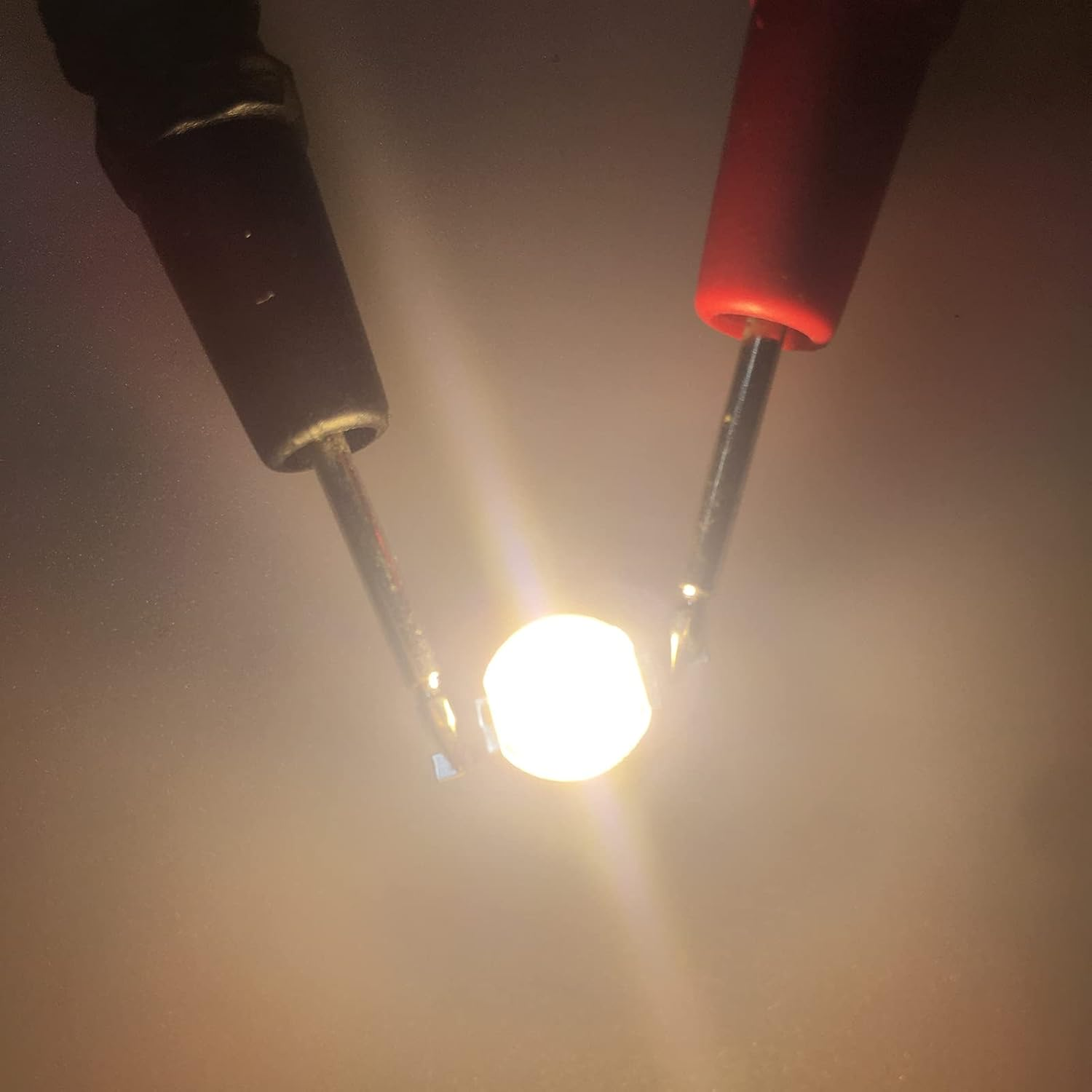 Ein schwarzer und ein roter Prüfspitzenkontakt leuchten eine kleine Glühbirne aus.