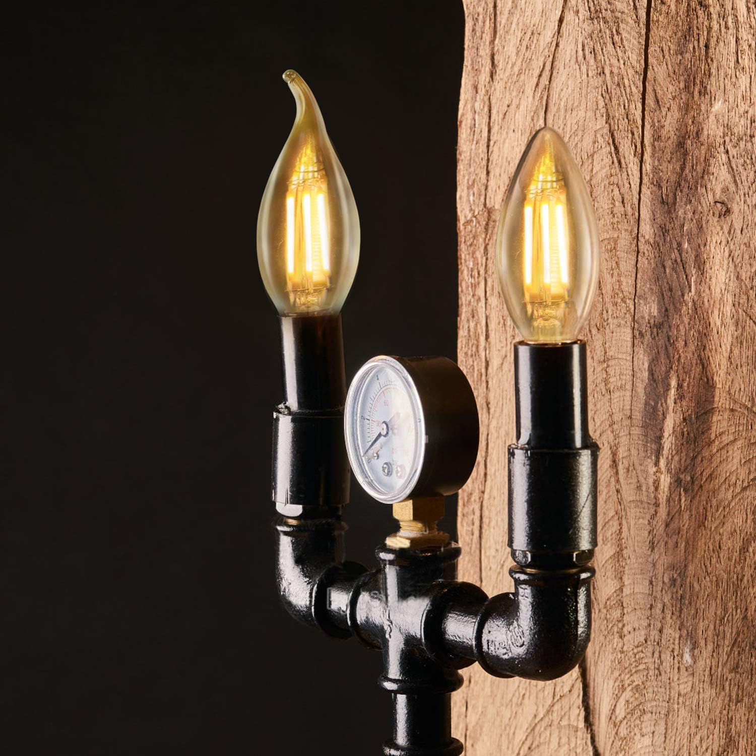 Zwei Glühbirnen über schwarzem Rohr mit Manometer an Holz.