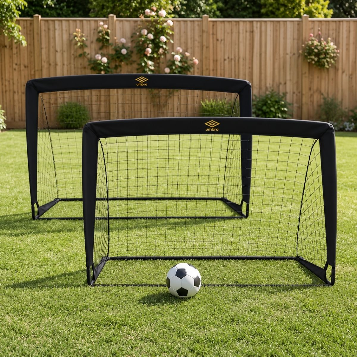 Zwei schwarze tragbare Fußballtore mit Netzen und ein schwarz-weißer Fußball auf grünem Rasen im Garten.