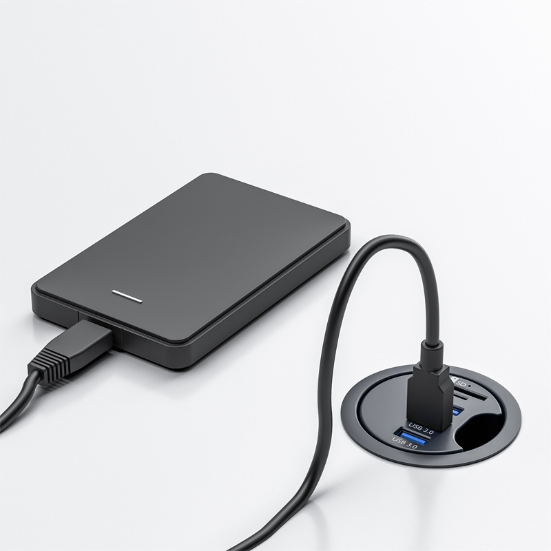 Eine schwarze externe Festplatte ist an einen USB-Hub auf einer weißen Oberfläche angeschlossen.