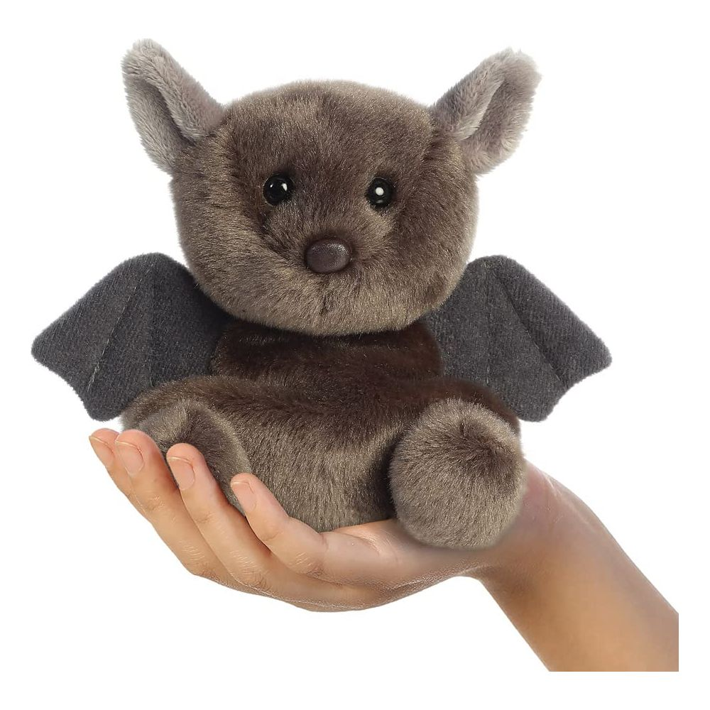 Ein braunes Plüschtier einer Fledermaus mit grauen Flügeln sitzt in einer Hand.
