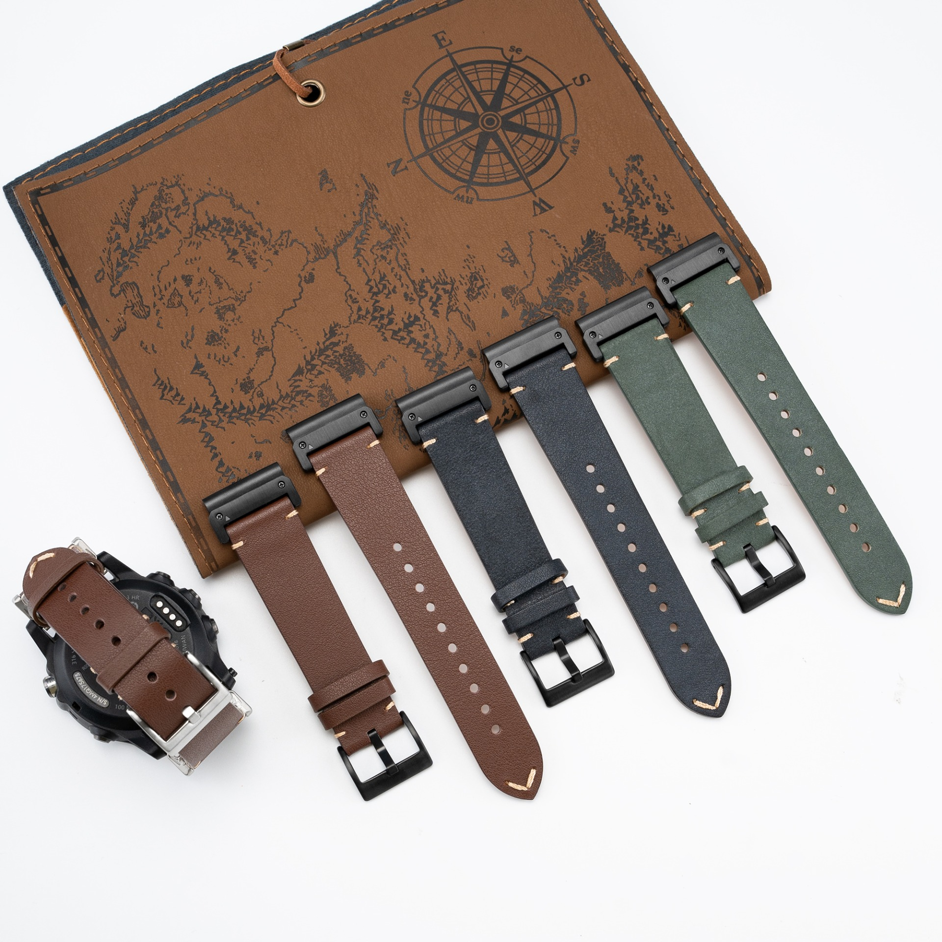 Eine Uhr mit braunen Lederriemen und ein Buch mit Kartenmotiv und Kompass.