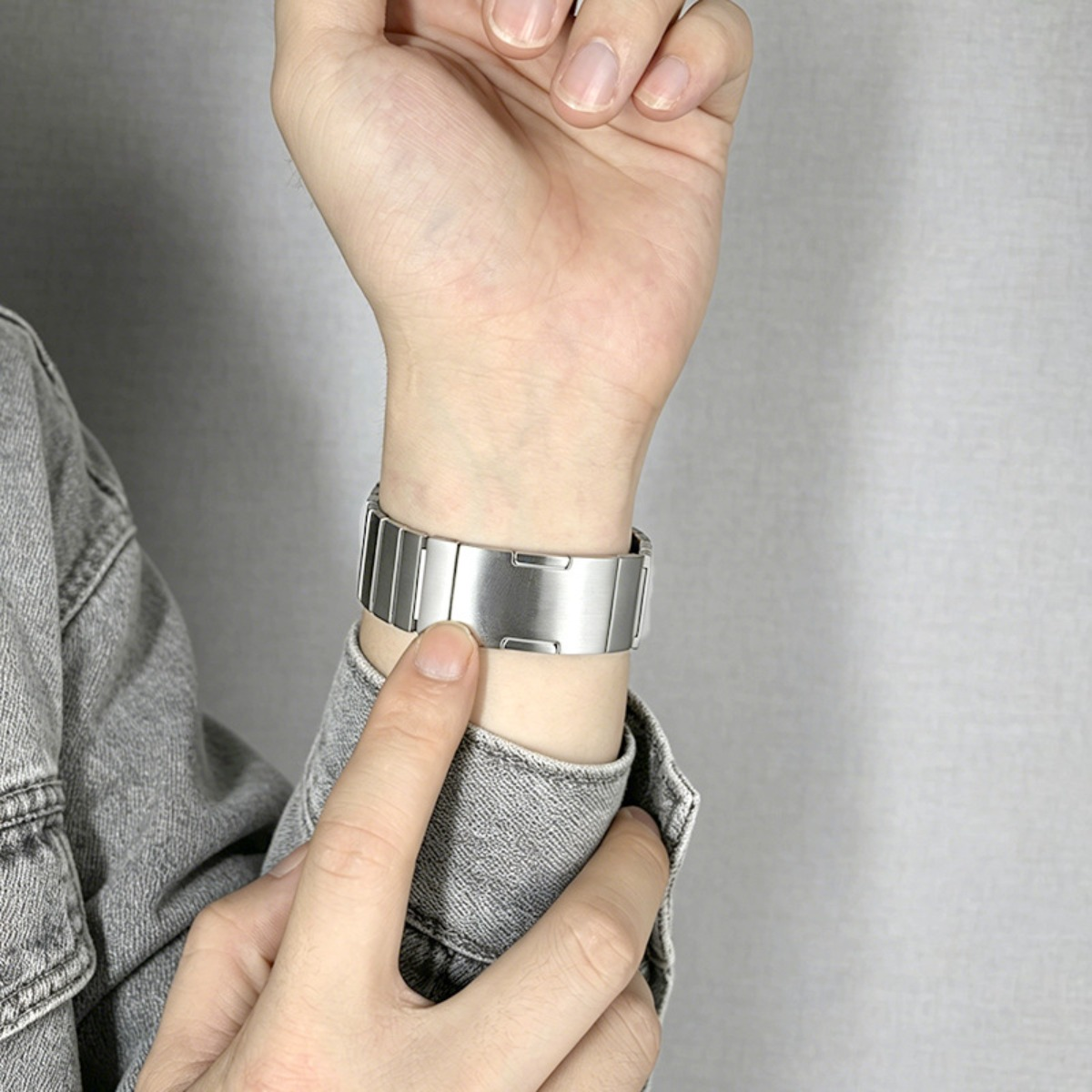 Eine Person trägt eine silberne Uhr mit einem Metallarmband an ihrem linken Handgelenk.