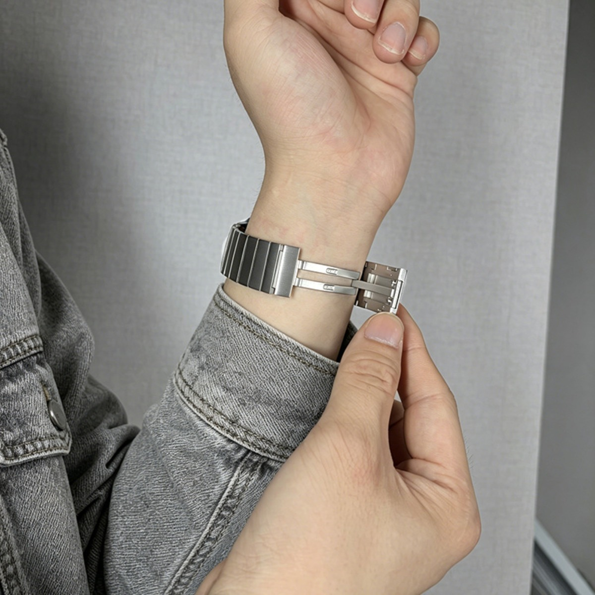 Eine Hand schlie×t ein silbernes Uhrenarmband an einem Handgelenk.