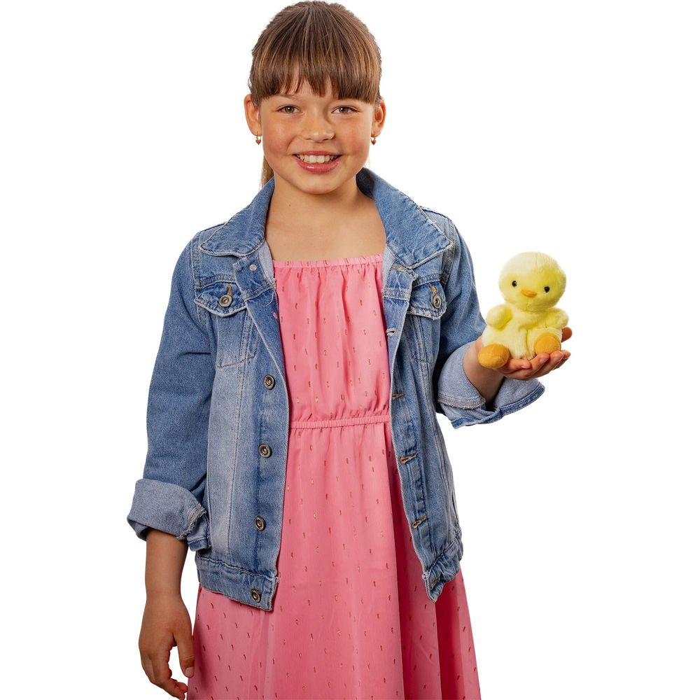 Ein Mädchen im Jeansjackett und pinkem Kleid hält ein gelbes Stoffküken.