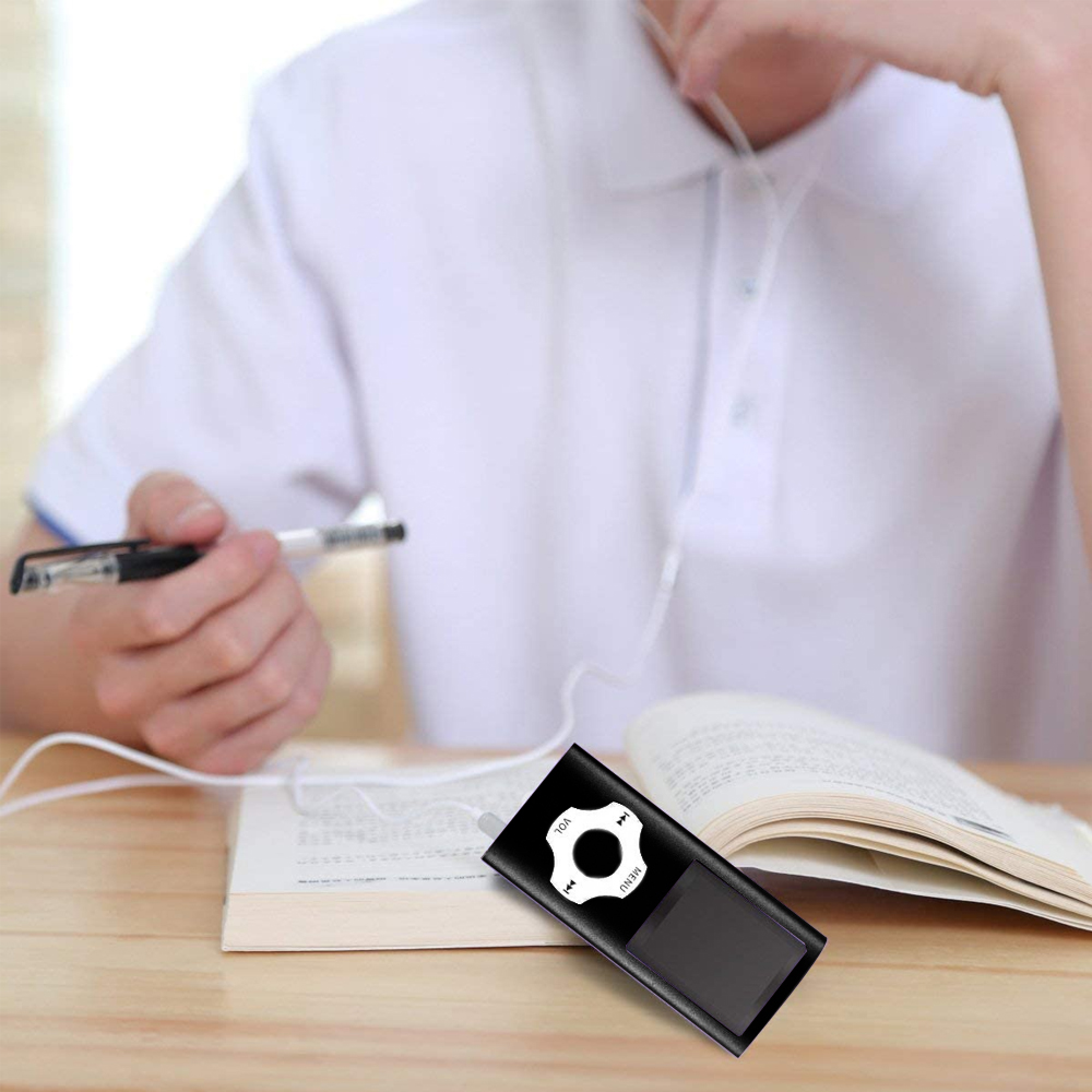 Jemand hält einen Stift über einem offenen Buch, ein MP3-Player liegt daneben.