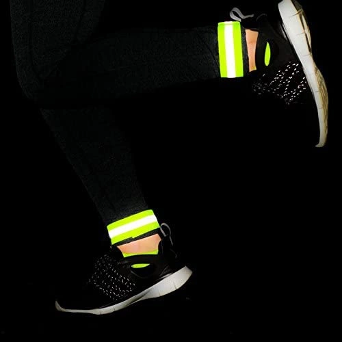 Person trägt schwarze Leggings, Turnschuhe und reflektierende Knöchelriemen.