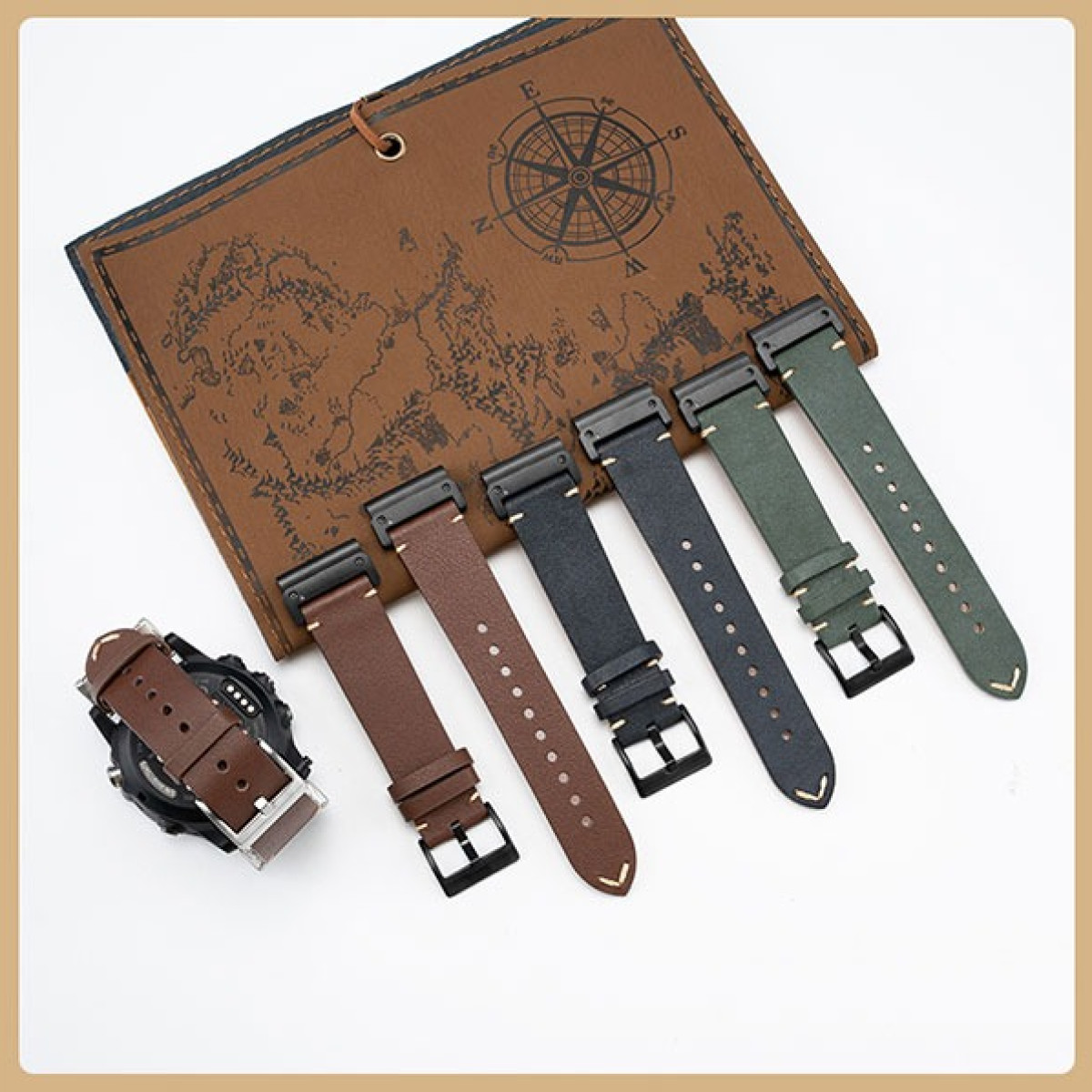 Braune und grüne Uhrenarmbänder liegen neben einer braunen Ledermappe mit Kompass.
