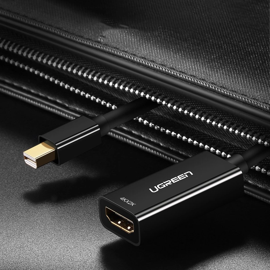 Un cavo UGREEN nero con estremità Mini DisplayPort e HDMI, vicino a una cerniera.